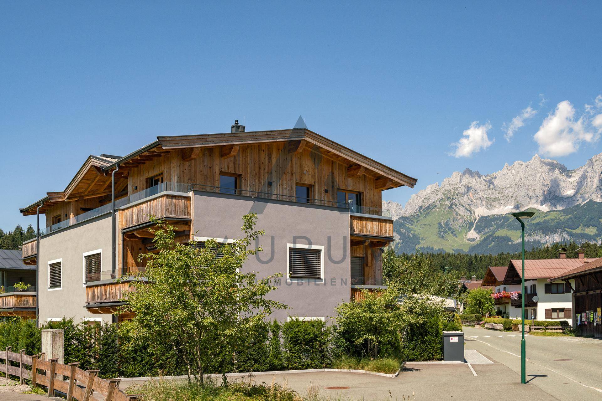 Attraktives Gebäude mit Holzverkleidung und Balkonen in alpiner Umgebung.
