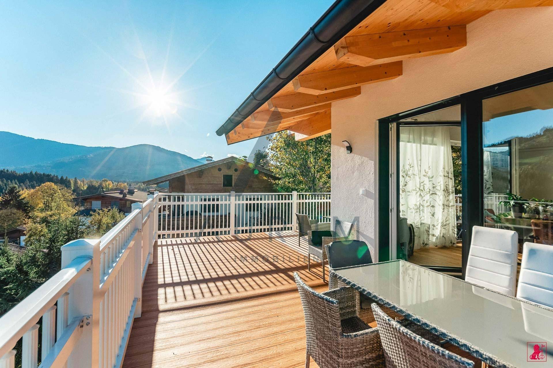 Heller Balkon mit Holzdach und Sitzgelegenheiten, bietet eine sonnige Aussicht auf die Berge.