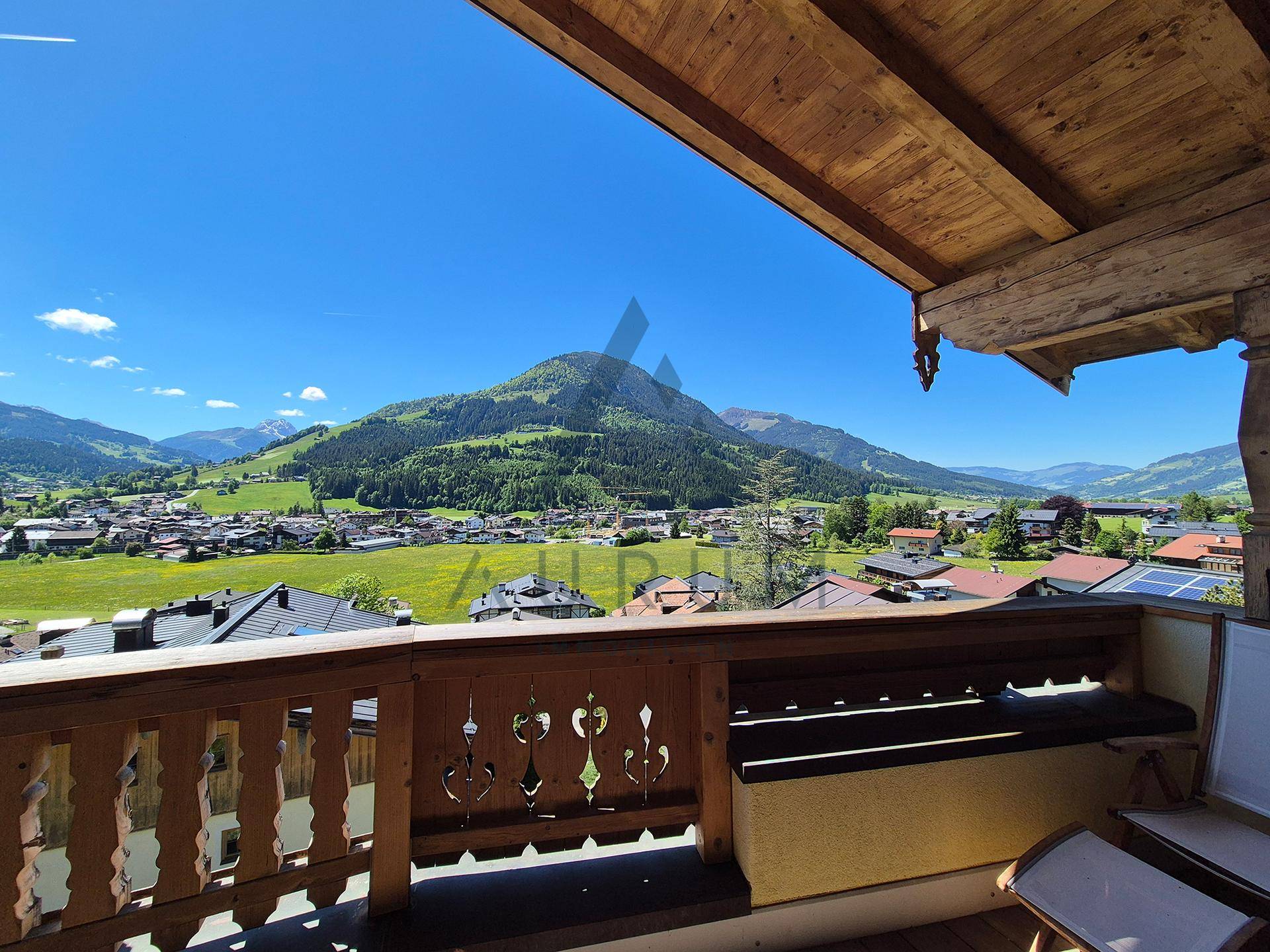 Gemütlicher Holzbalkon mit integrierter Sitzbank und weitem Ausblick auf das idyllische Bergpanorama.
