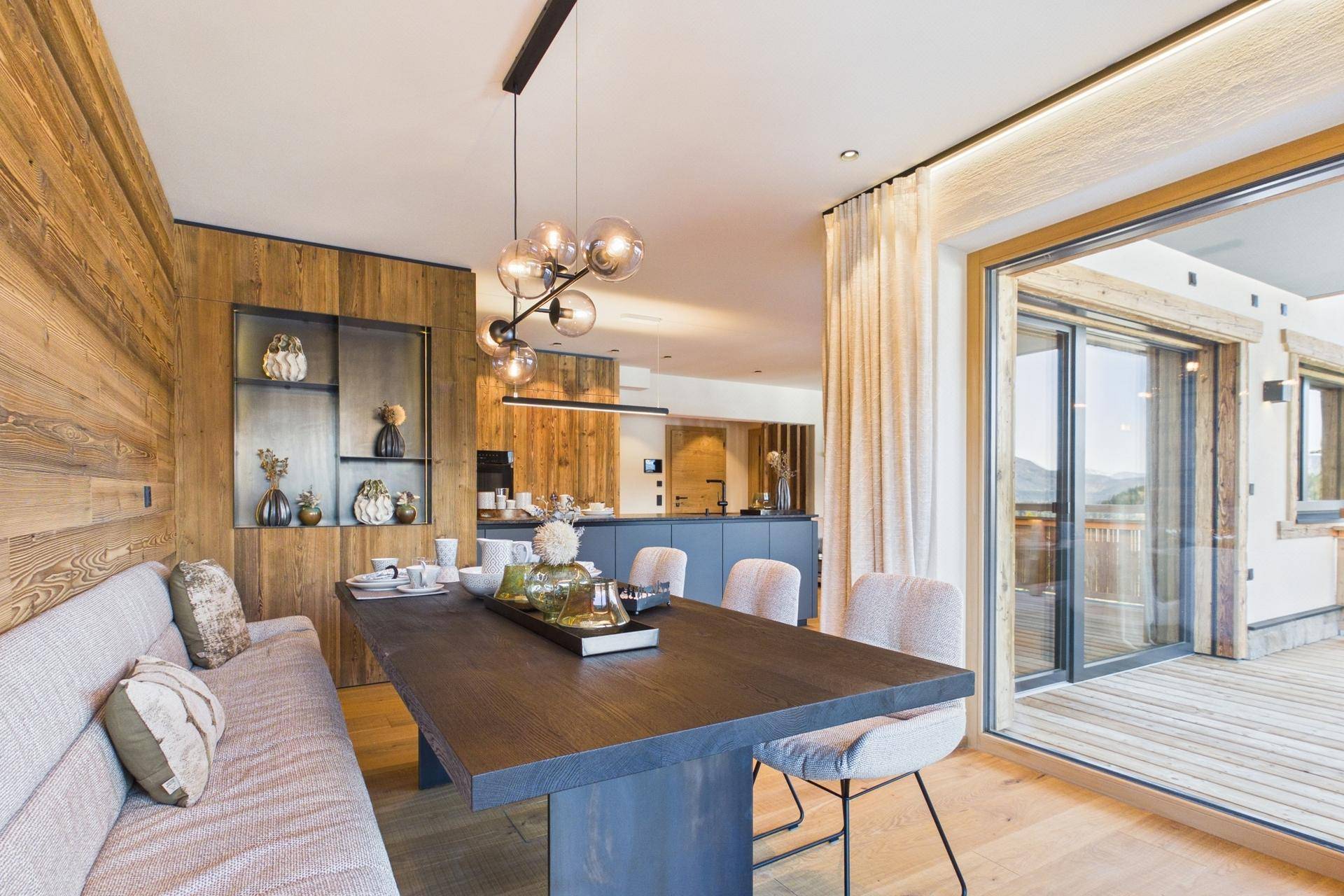 Stilvoller Essbereich mit Holzwand, großem Esstisch und Zugang zur Terrasse.