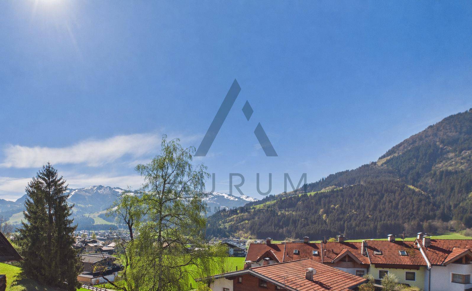 Weite Aussicht auf die umliegende Berglandschaft und das Tal unter strahlend blauem Himmel.