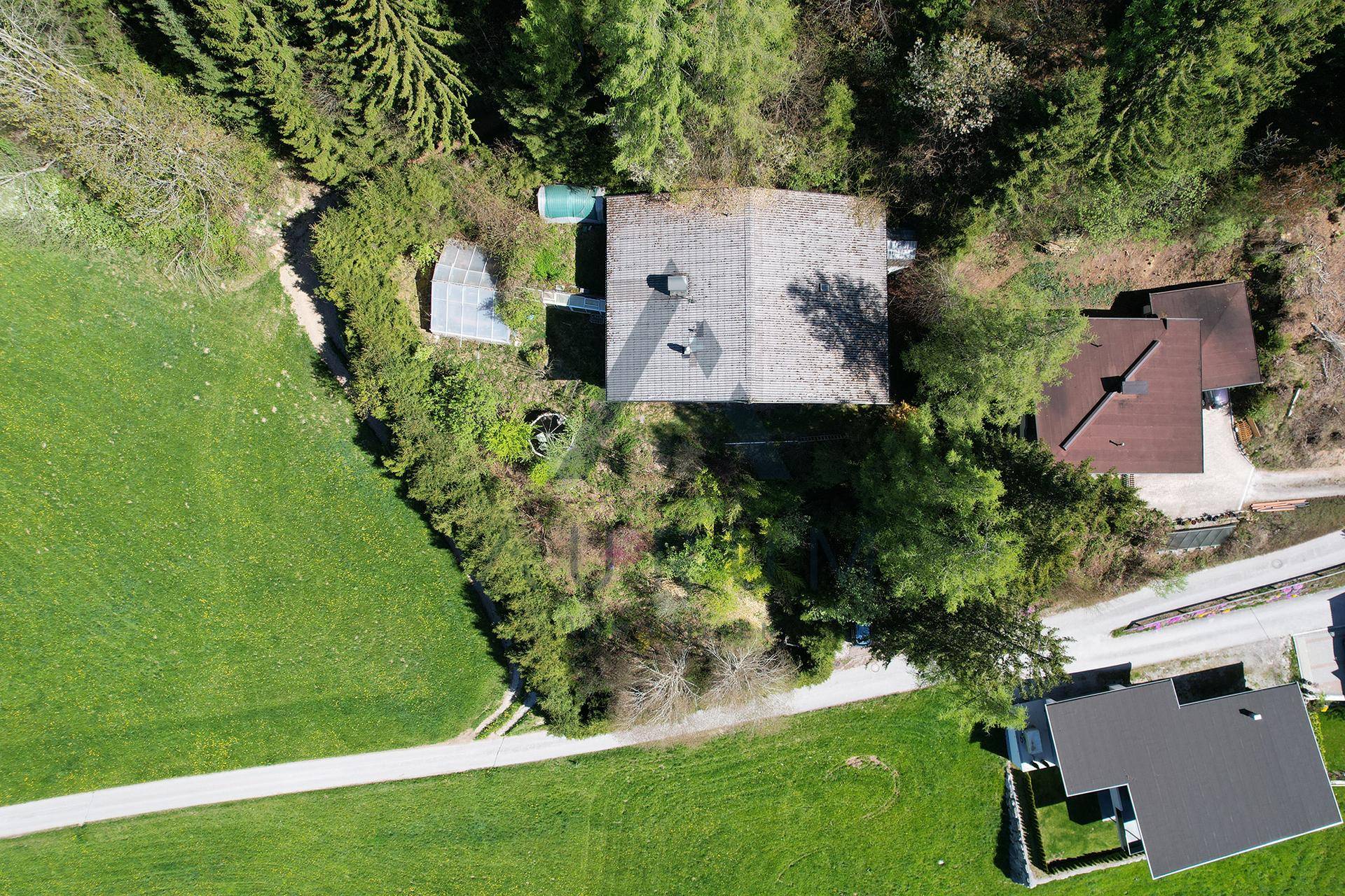 Vogelperspektive des Anwesens mit Haupthaus, Nebengebäuden und umliegender Grünfläche.