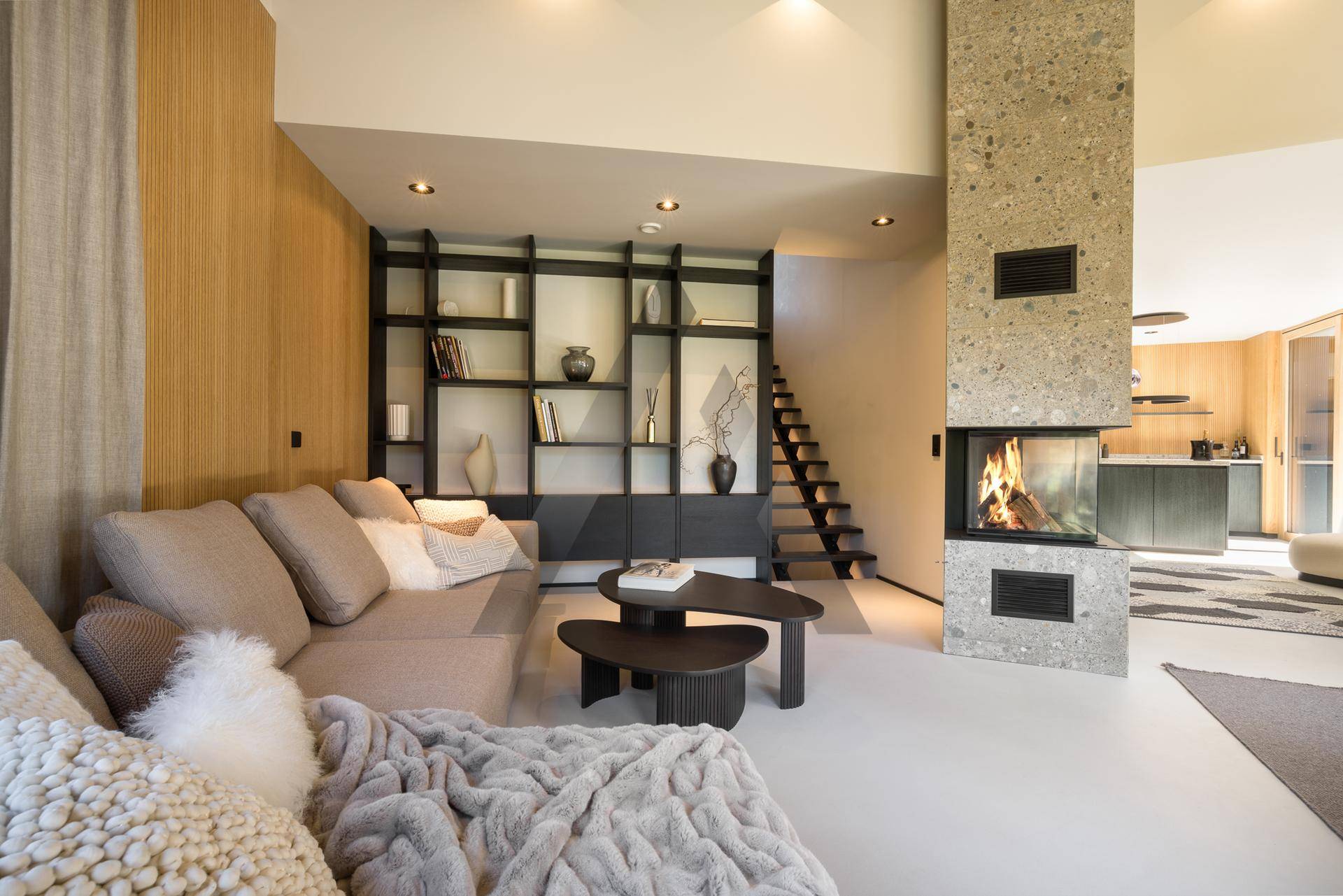 Gemütliches Wohnzimmer mit modernem Kamin, integriertem Regal und Zugang zur Küche.