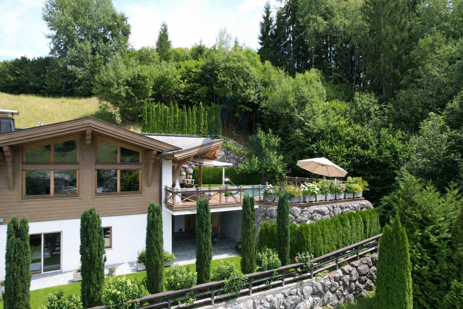 Luxuriöses Haus mit Außenpool, Terrassen und gepflegter Gartenanlage in alpiner Umgebung.
