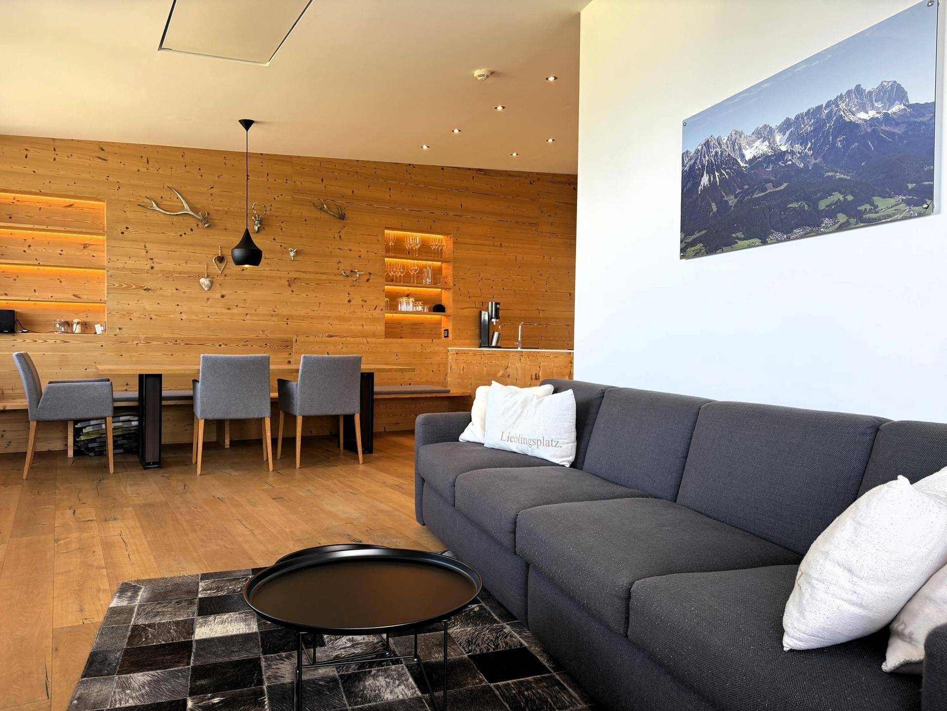 Offener Wohn- und Essbereich mit Holzwänden, modernem Sofa und Esstisch für gesellige Runden.