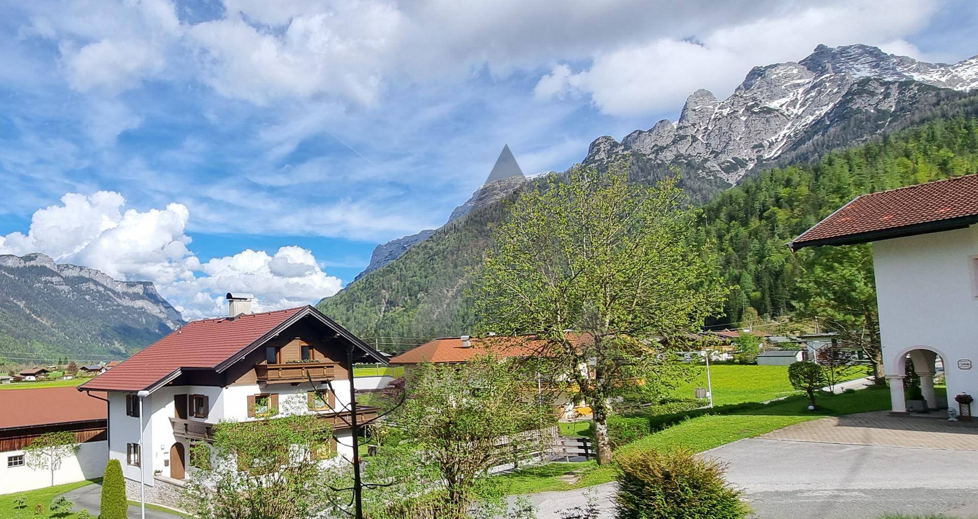 Idyllischer Ausblick auf die umliegende Bergwelt mit traditionellen Häusern und üppiger Vegetation.