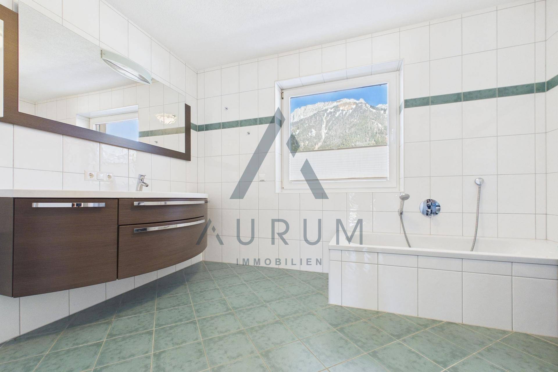 Geräumiges Badezimmer mit Badewanne, Waschtisch und Fenster mit Bergblick.