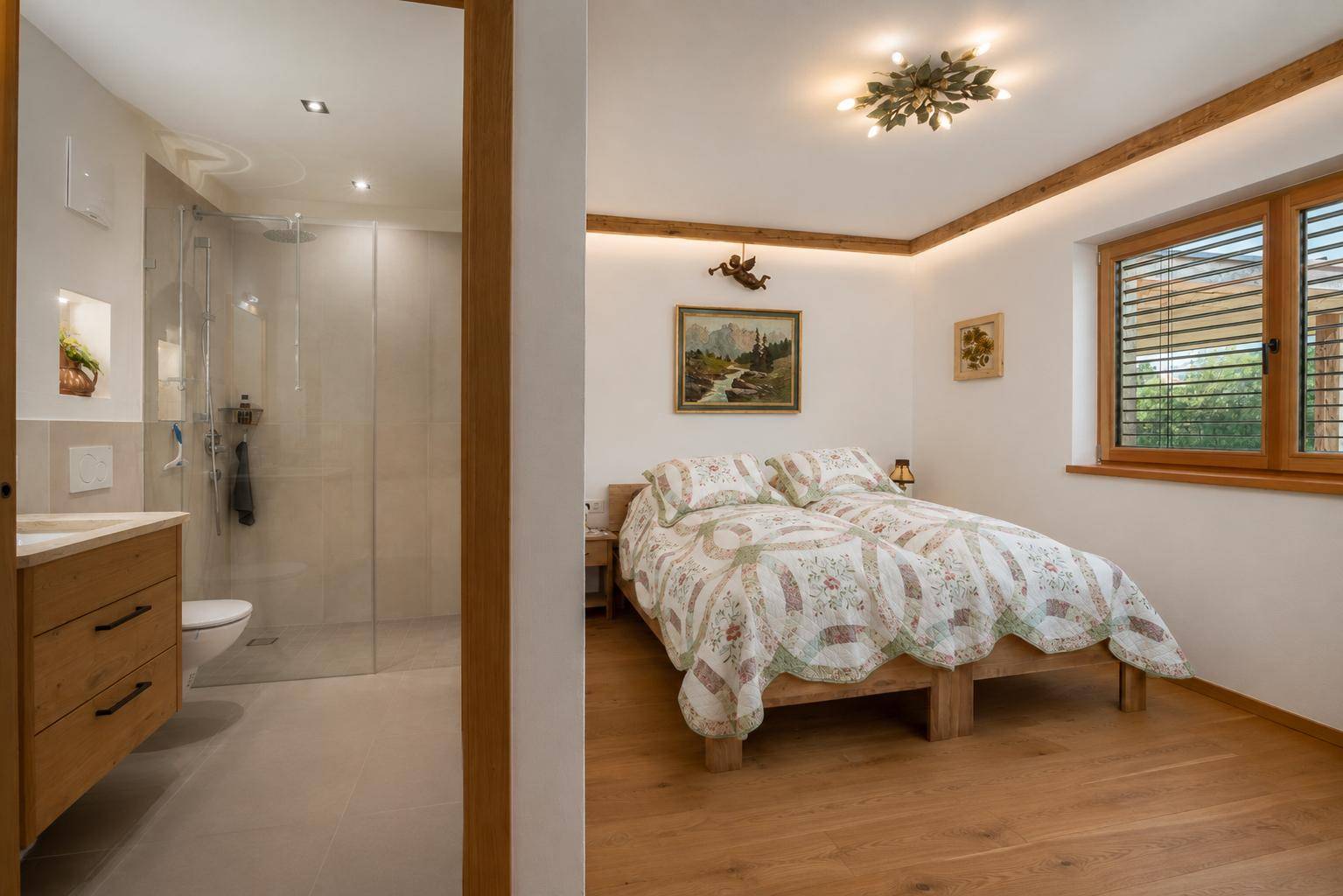 Helles Schlafzimmer mit Holzboden und angrenzendem Badezimmer mit Dusche.