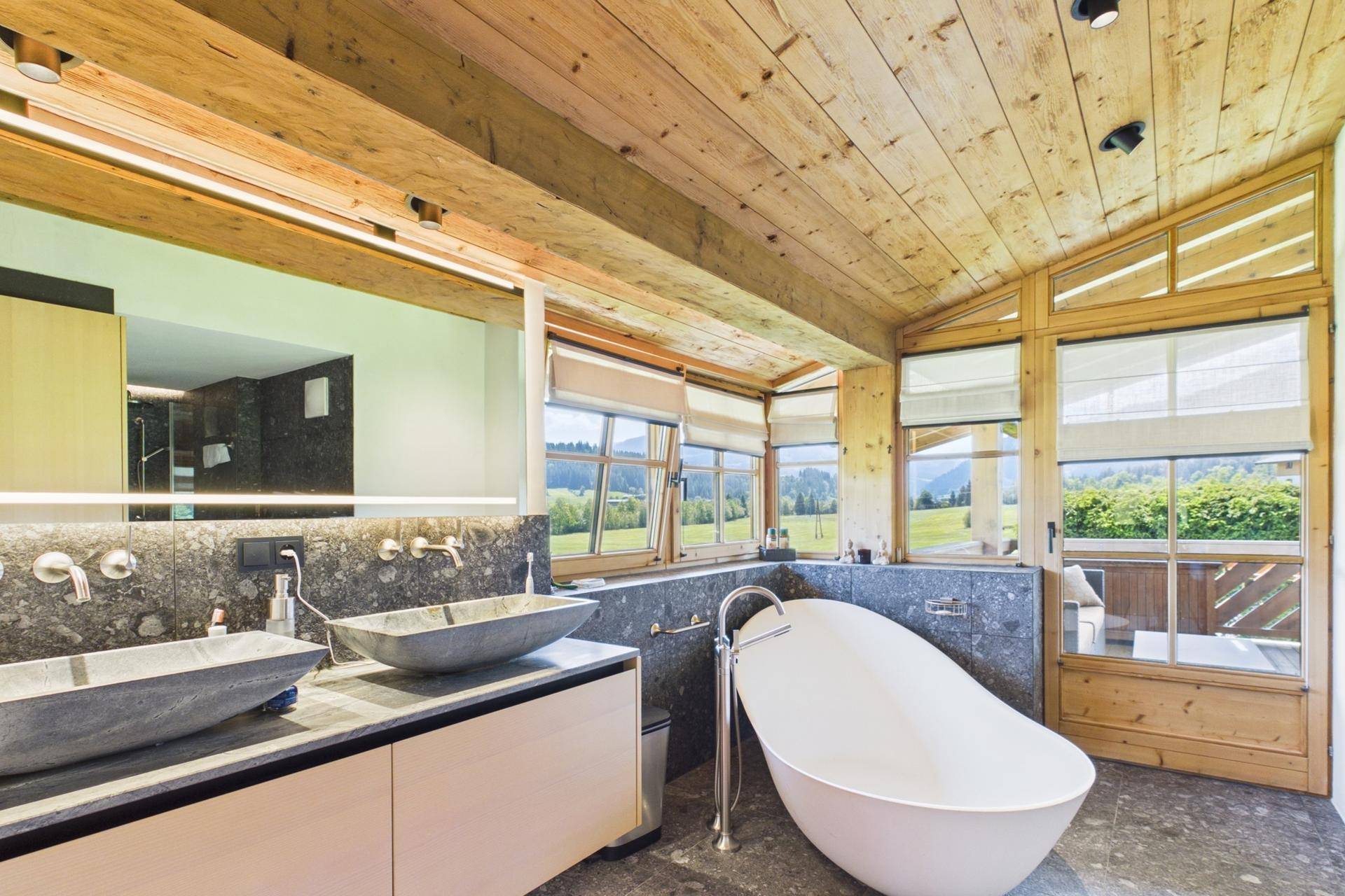 Luxuriöses Badezimmer mit freistehender Badewanne, Doppelwaschbecken und Holzbalkendecke.