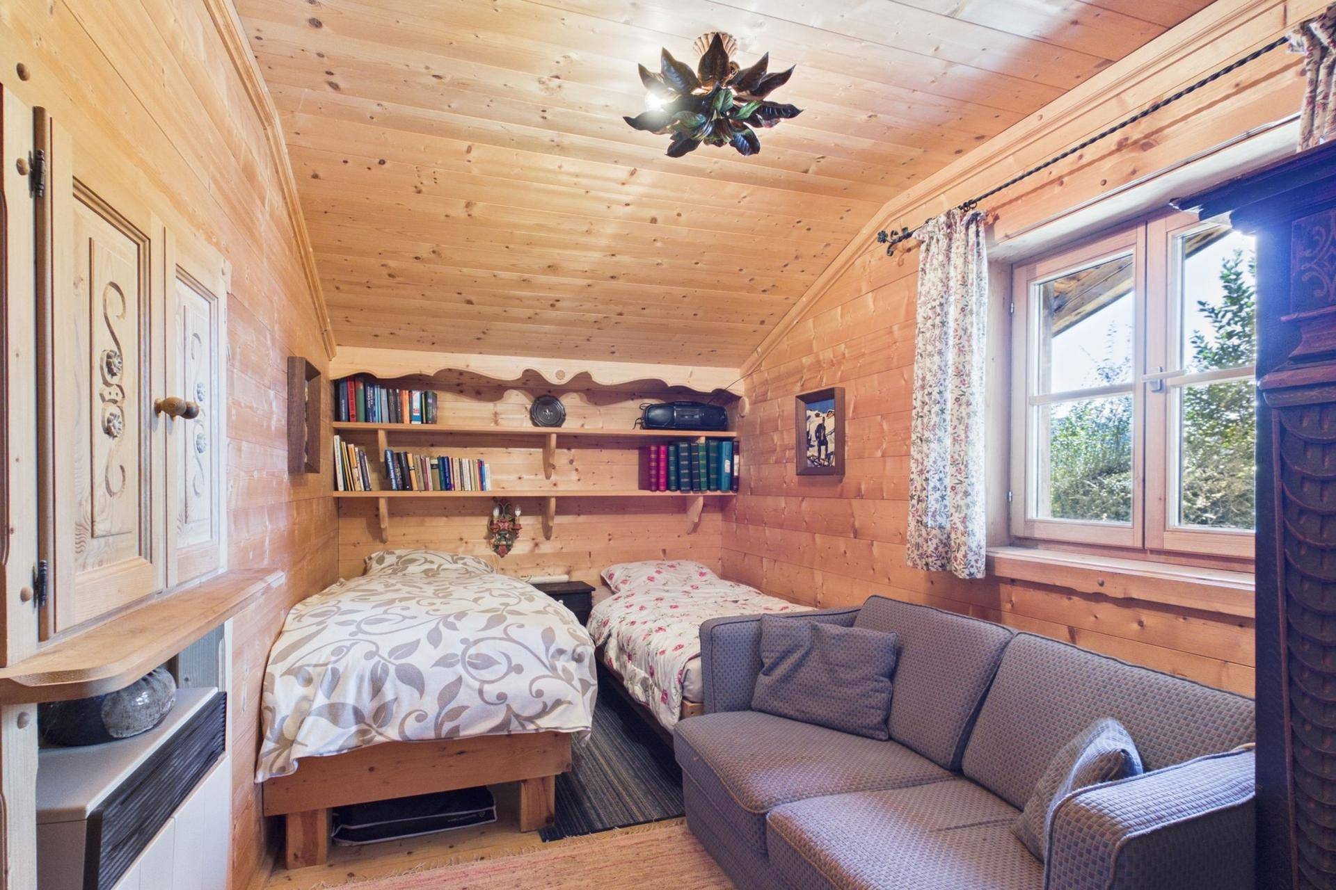 Gemütliches Schlafzimmer mit zwei Einzelbetten, Holzvertäfelung und Bücherregal.