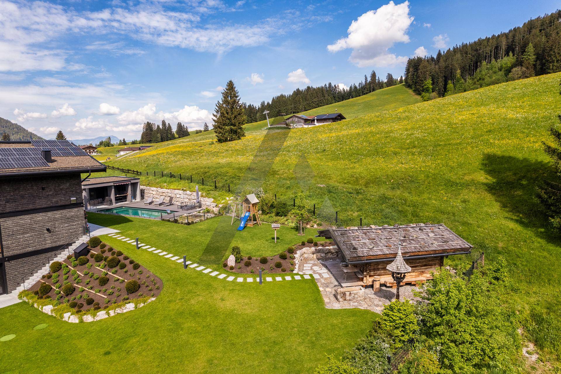 Gepflegter Gartenbereich mit Spielplatz, Gartenhaus und weitem Blick auf die Natur.