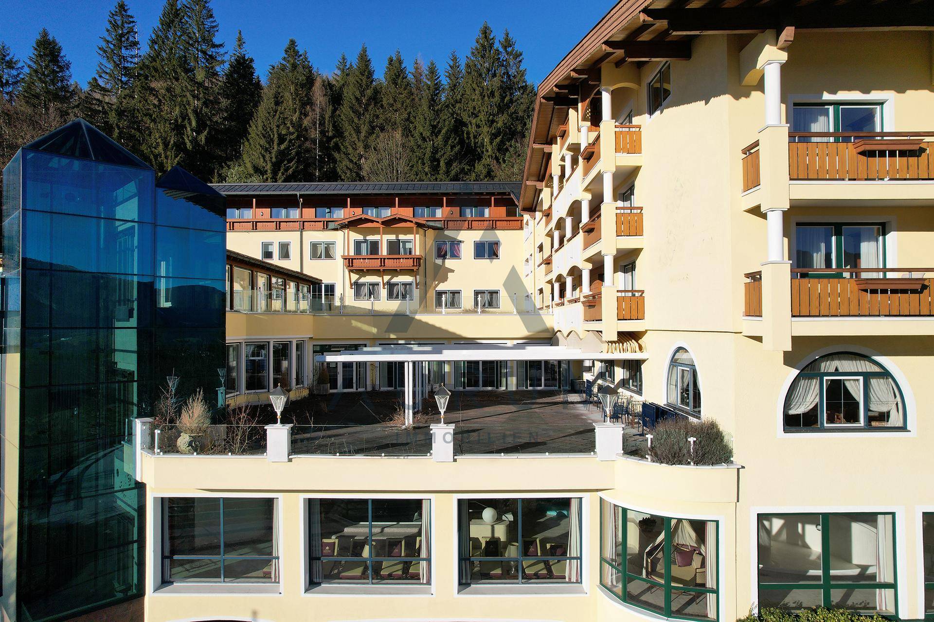 Nahaufnahme der Gebäudefassade mit mehreren Balkonen, einer großen Terrasse und einem markanten Glasaufzug.