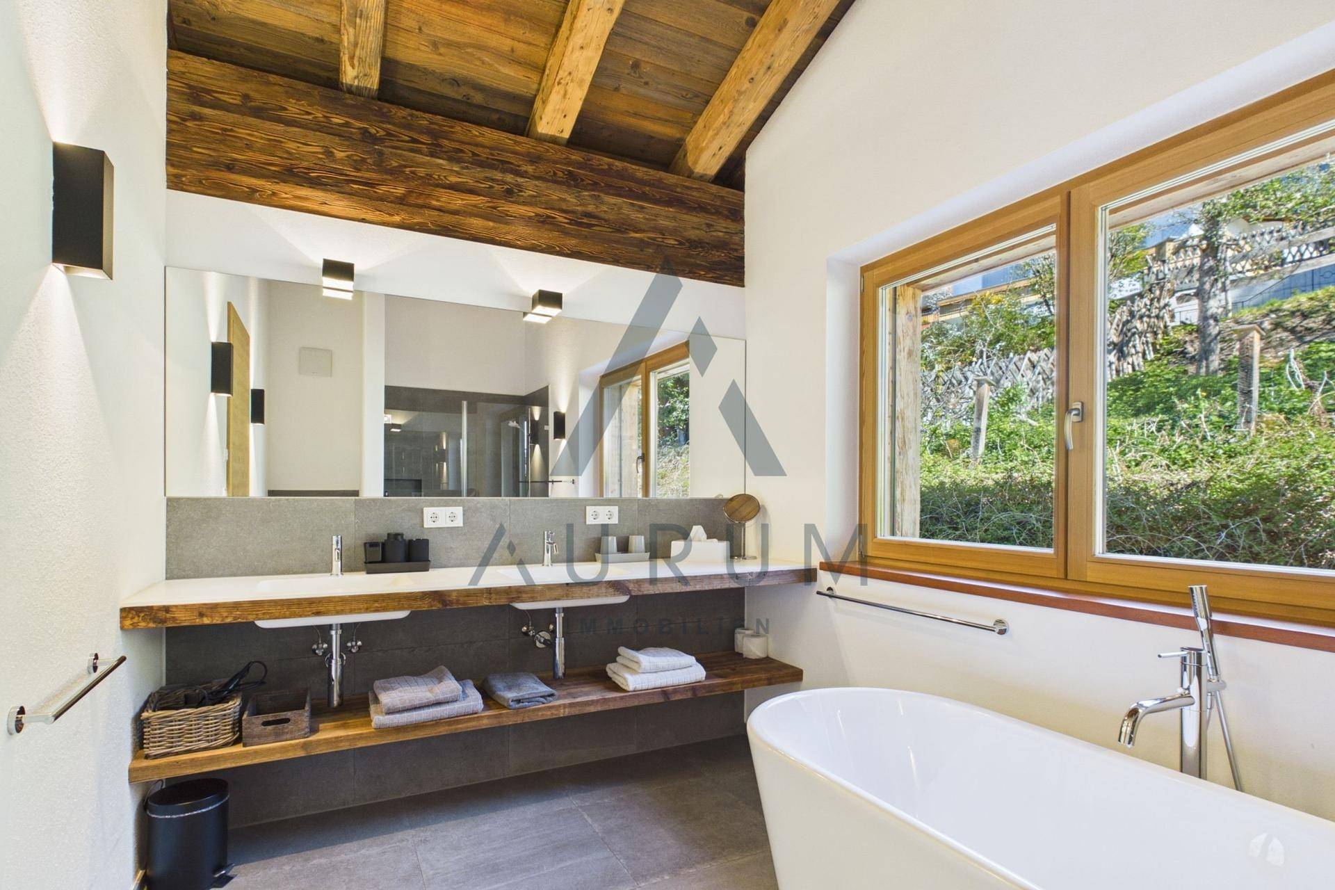 Modernes Badezimmer mit freistehender Badewanne, Doppelwaschbecken und großem Fenster.