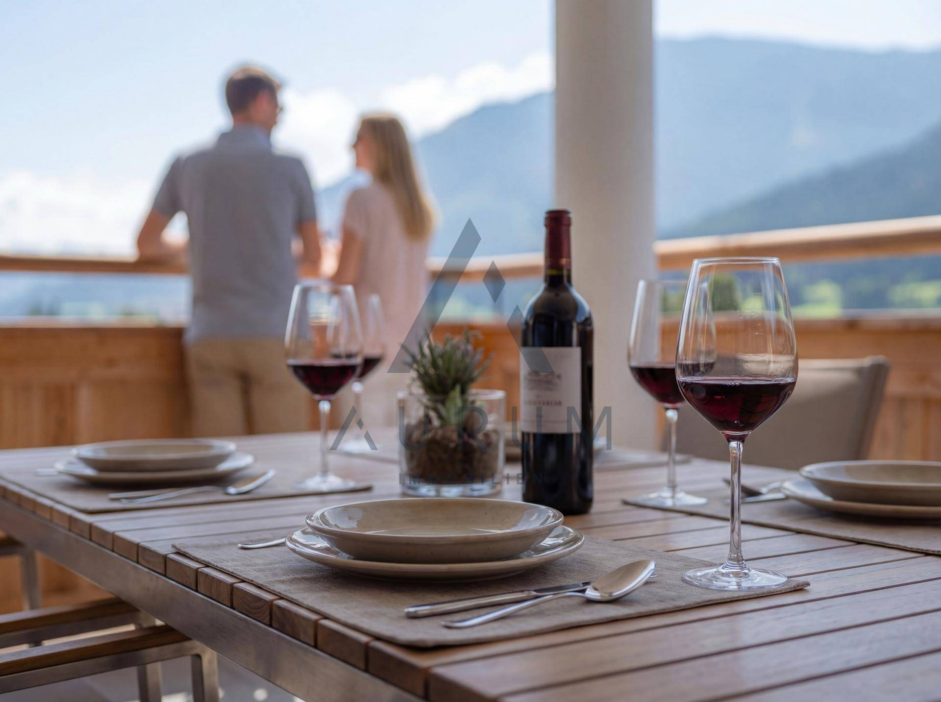 Detailaufnahme eines gedeckten Tisches auf dem Balkon mit Wein und Bergblick im Hintergrund.
