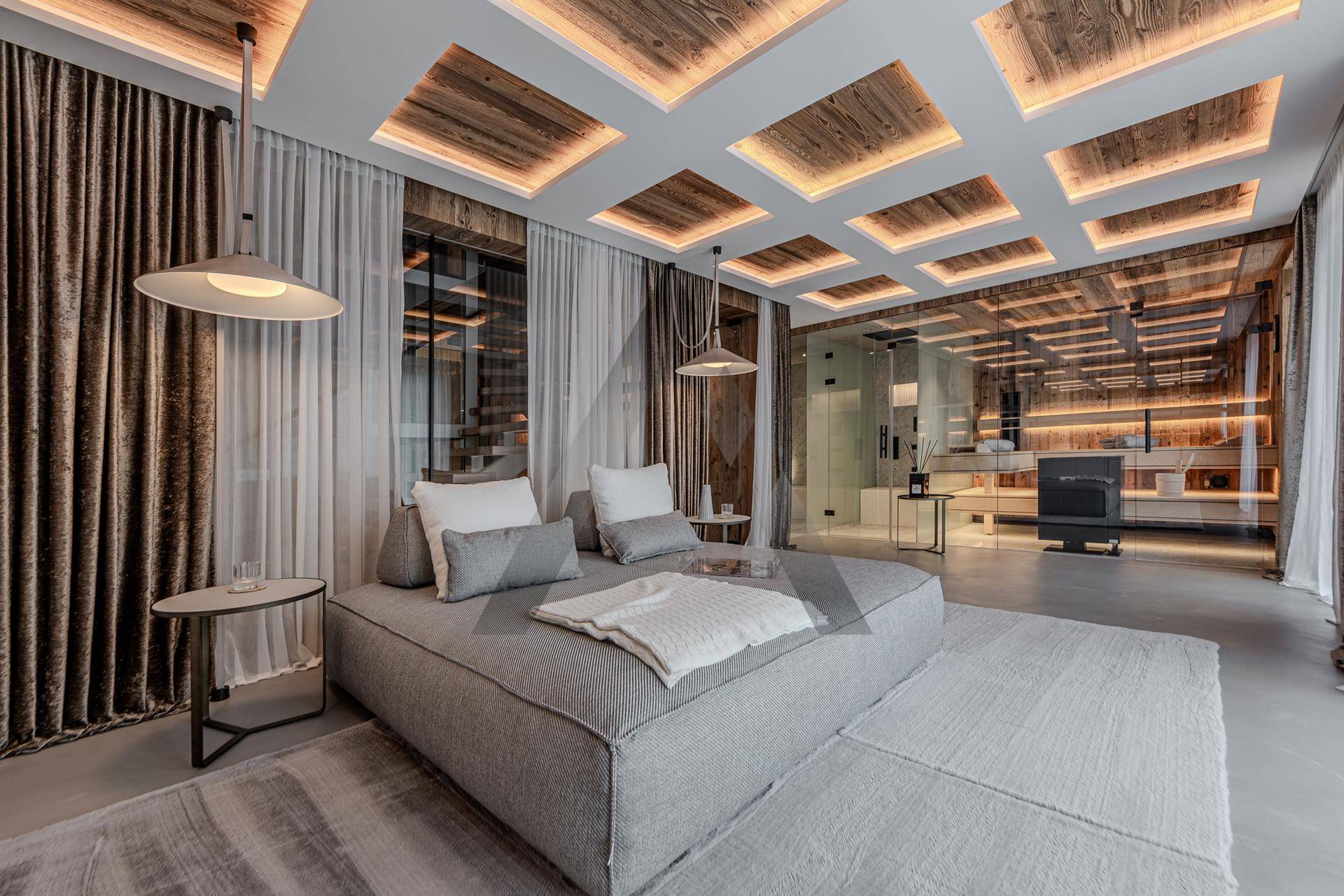 Modernes Schlafzimmer mit stilvoller Deckenbeleuchtung, großem Tagesbett und Glaswänden zu einem angrenzenden Bereich.