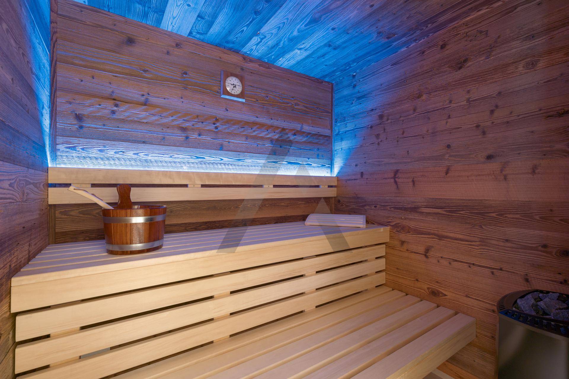 Private Sauna mit Holzverkleidung, Bänken und stimmungsvoller Beleuchtung.