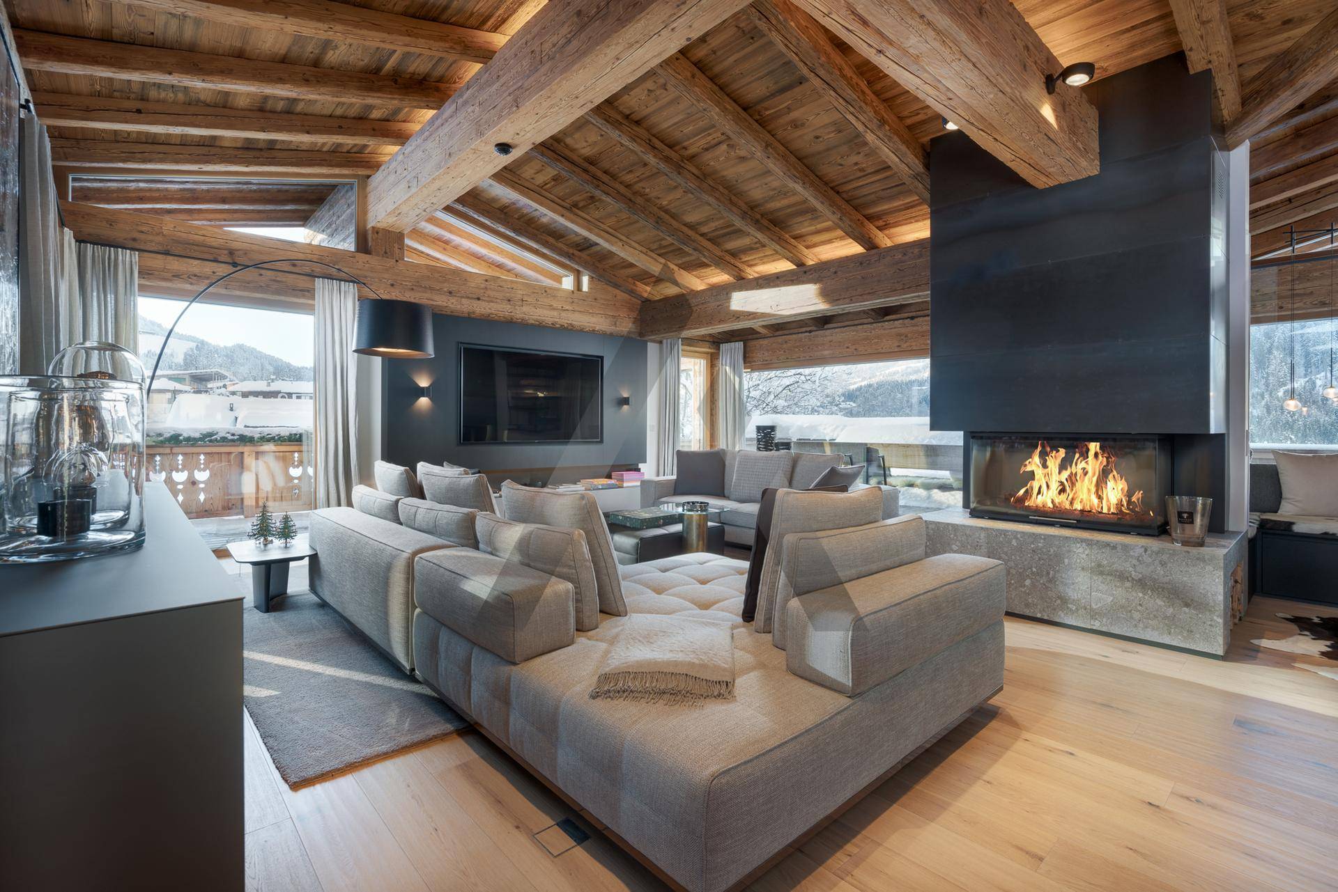 Gemütlicher Wohnbereich mit großem Sofa, Kamin und Holzbalkendecke, ideal für entspannte Abende.