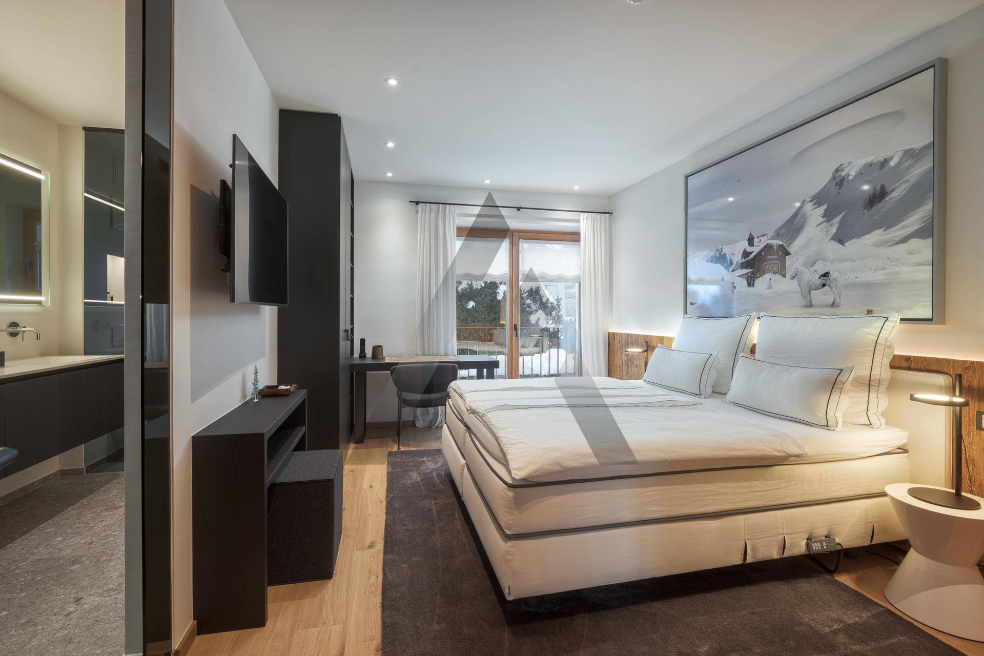 Komfortables Schlafzimmer mit Doppelbett, Holzboden und Zugang zu einem Balkon mit Bergblick.