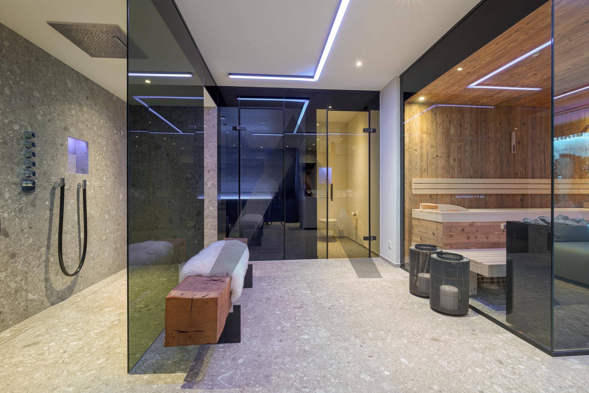 Exklusiver Wellnessbereich mit moderner Regendusche und holzverkleideter Sauna für pure Entspannung.