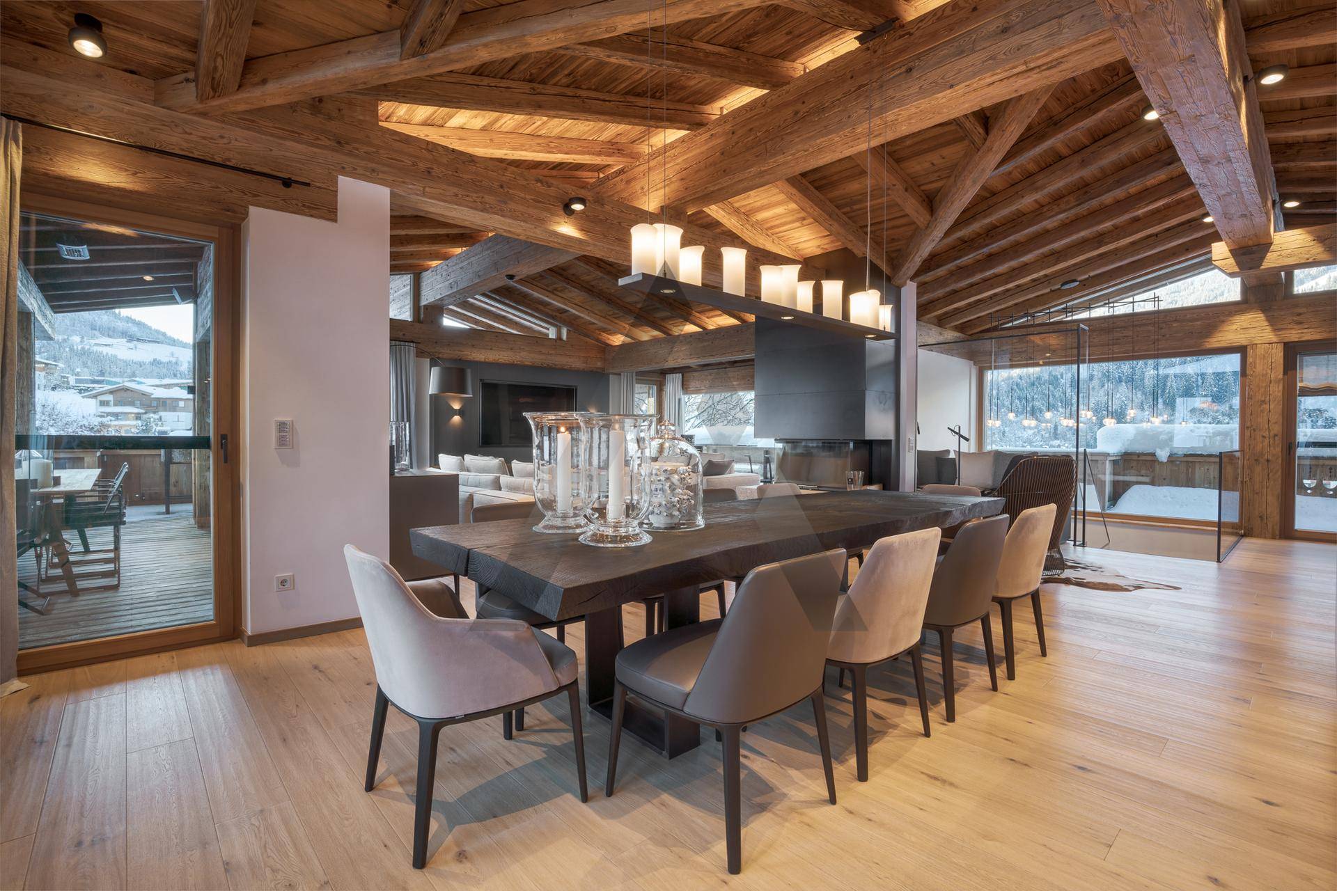 Heller Essbereich mit großem Holztisch, modernen Stühlen und Zugang zu einem Balkon mit Bergblick.