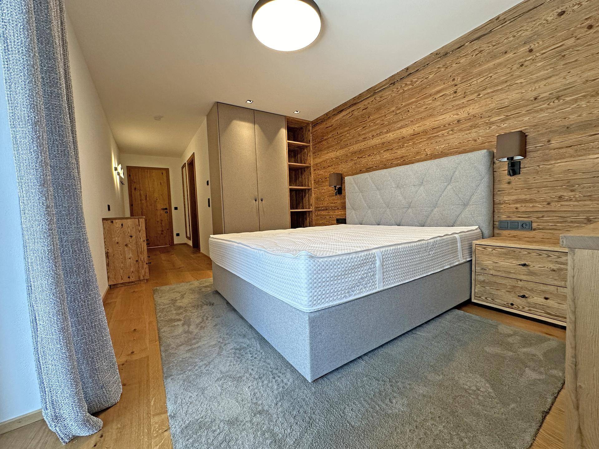 Helles Schlafzimmer mit Doppelbett, Holzwänden und praktischen Einbauschränken.