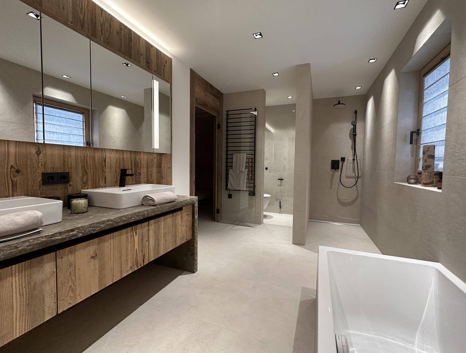 Modernes Badezimmer mit Doppelwaschbecken, begehbarer Dusche, Badewanne und Holzelementen.