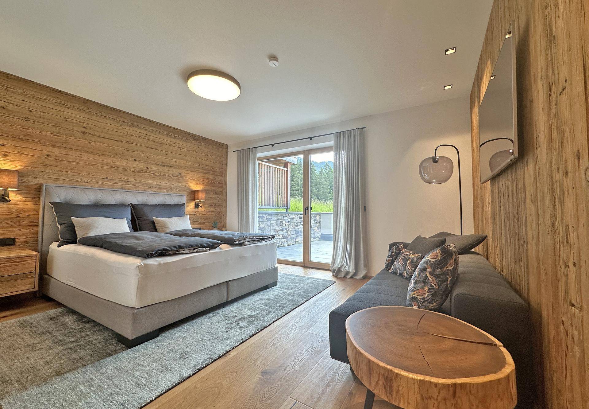 Gemütliches Schlafzimmer mit Doppelbett, Holzwänden und direktem Zugang zur Terrasse.