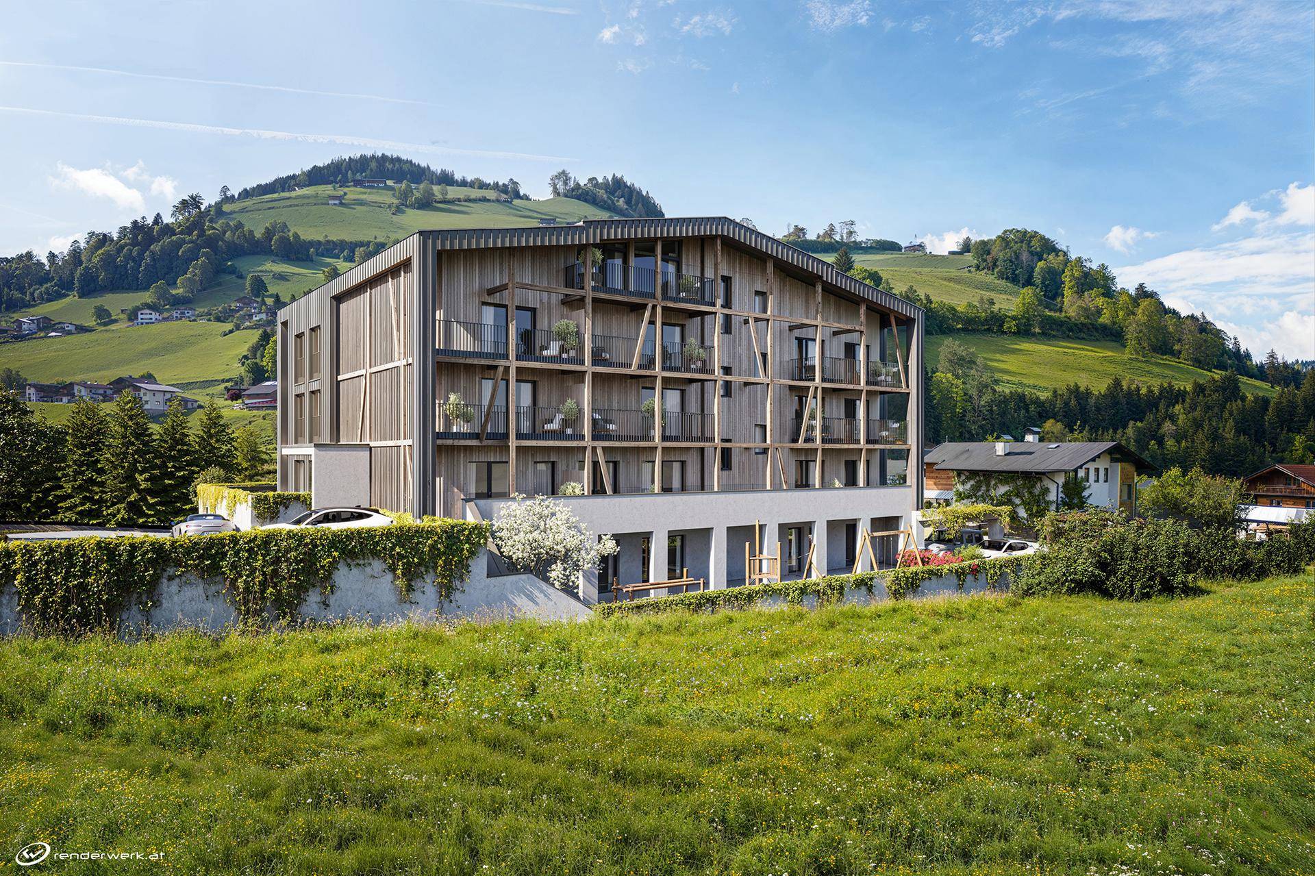 Modernes Mehrfamilienhaus in alpiner Landschaft mit Holzfassade und Balkonen, umgeben von grünen Hügeln.