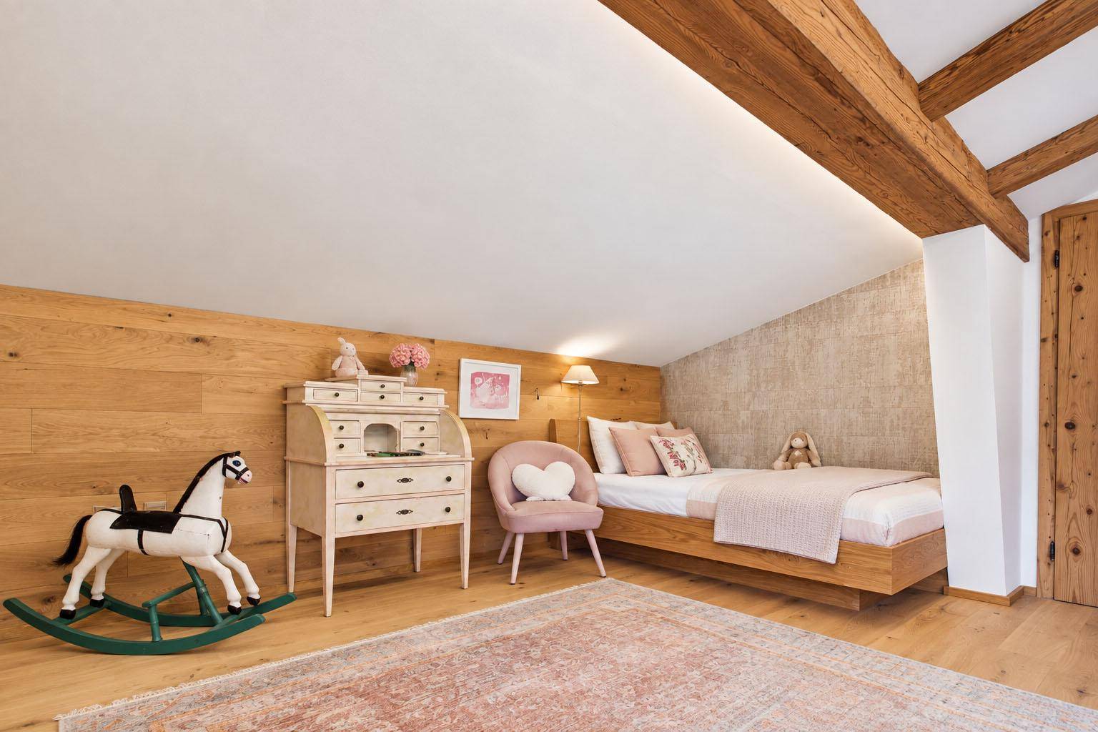 Kinderzimmer im Dachgeschoss mit Holzbalken, Holzwänden und liebevoller Einrichtung.