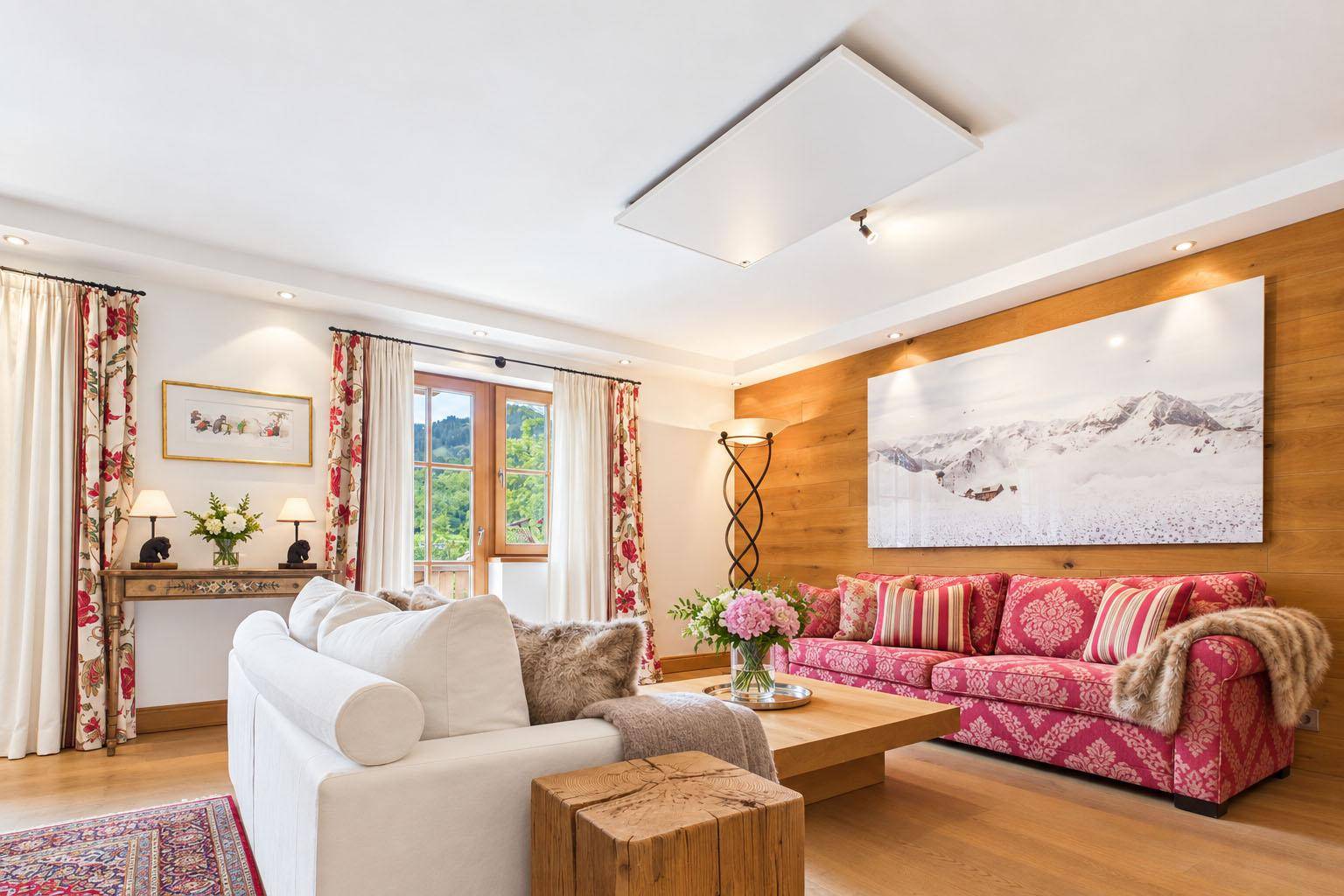 Helles Wohnzimmer mit bequemen Sofas, Holzakzenten und einem großen Bergpanorama-Bild an der Wand.