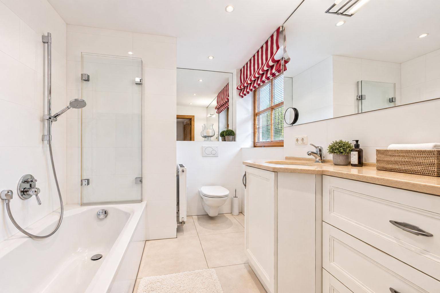 Modernes Badezimmer mit Badewanne, Waschtisch und Wand-WC in hellen Farbtönen.
