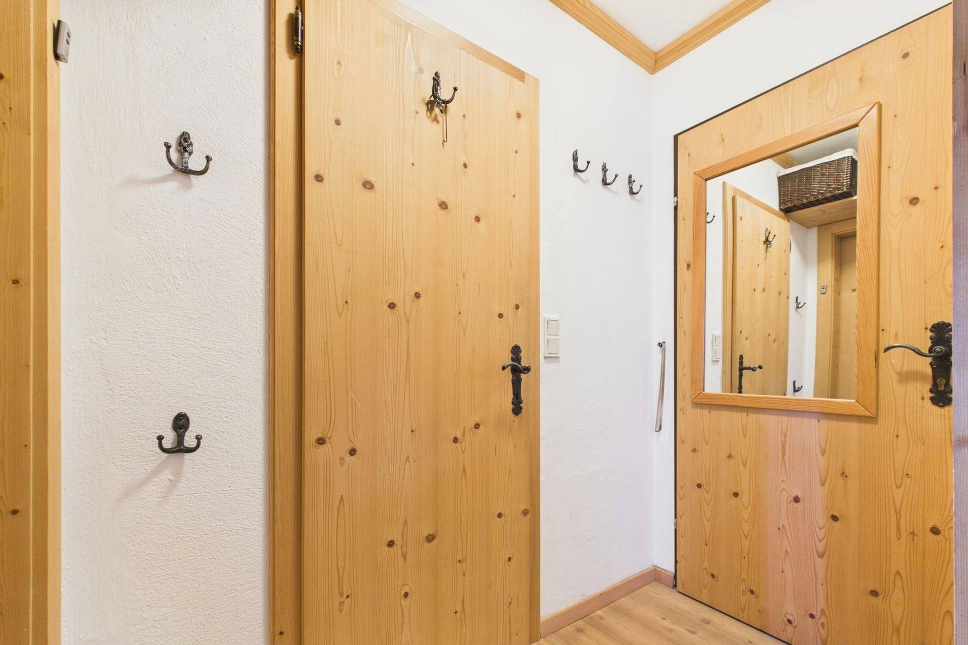 Heller Flur mit Holztüren, Garderobenhaken und einem Spiegel für den Eingangsbereich.