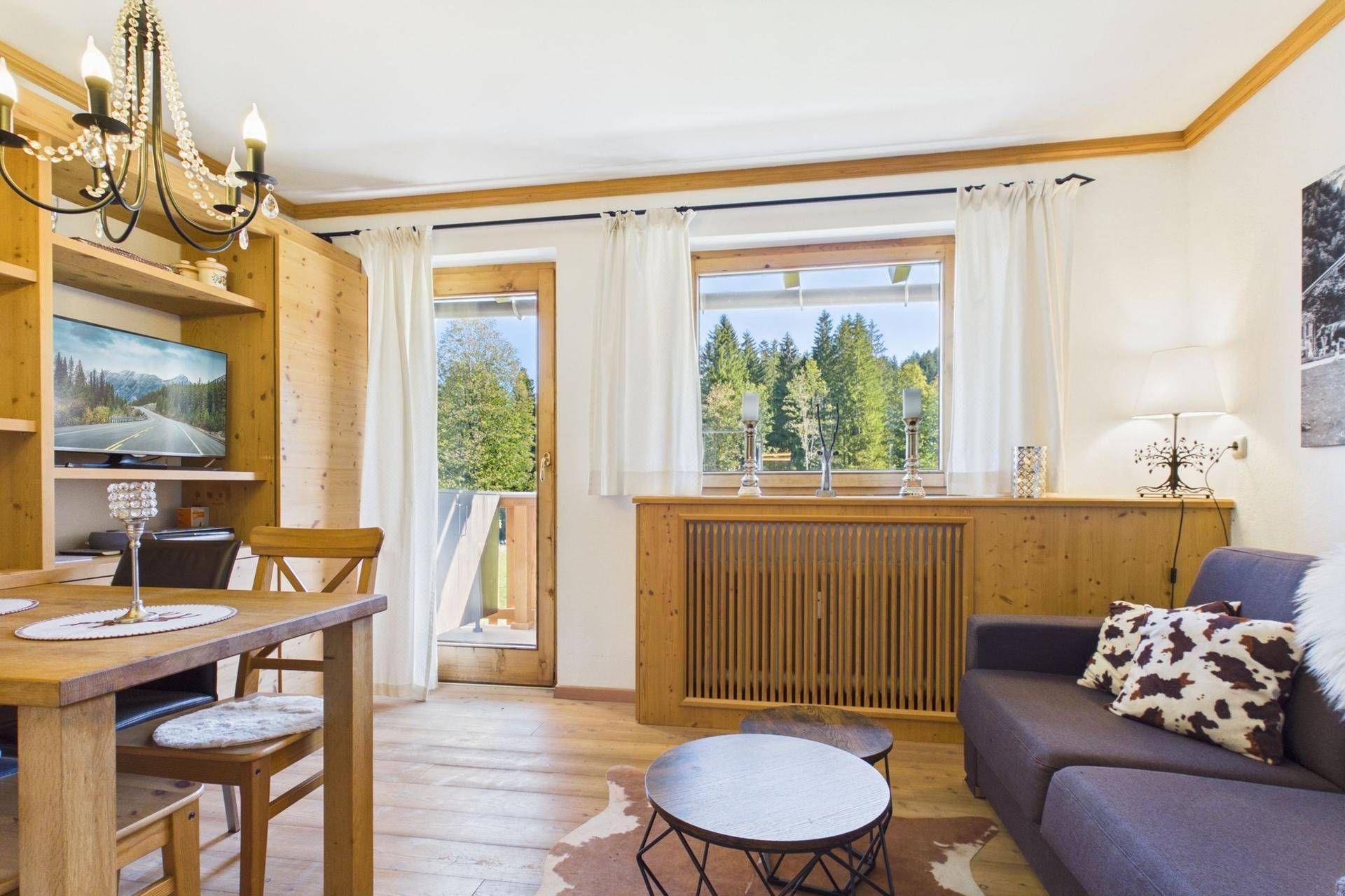Lichtdurchfluteter Wohn-Essbereich mit Holzeinrichtung und Zugang zum sonnigen Balkon.