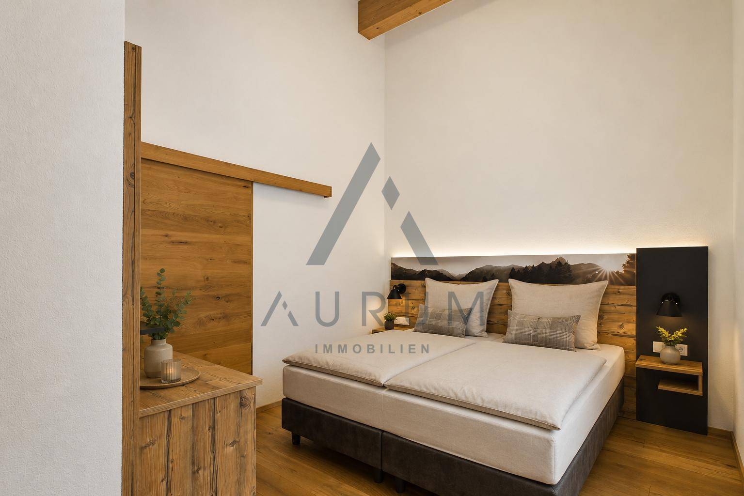 Schlafzimmer mit Holzboden, modernem Kopfteil, indirekter Beleuchtung und Holzschiebetür.
