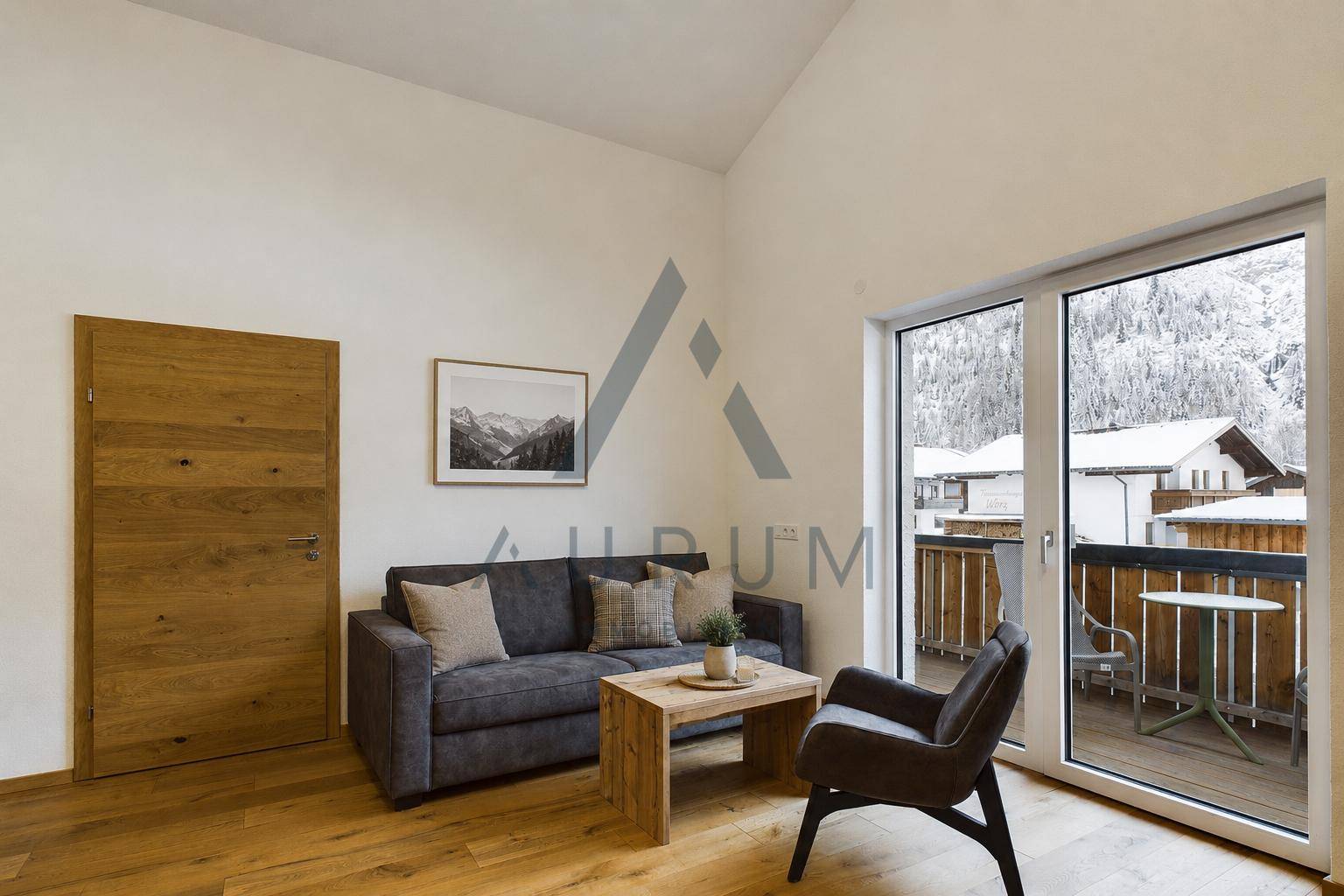 Gemütliches Wohnzimmer mit Holzboden, großem Fenster, Balkonzugang und Blick auf die verschneiten Berge.