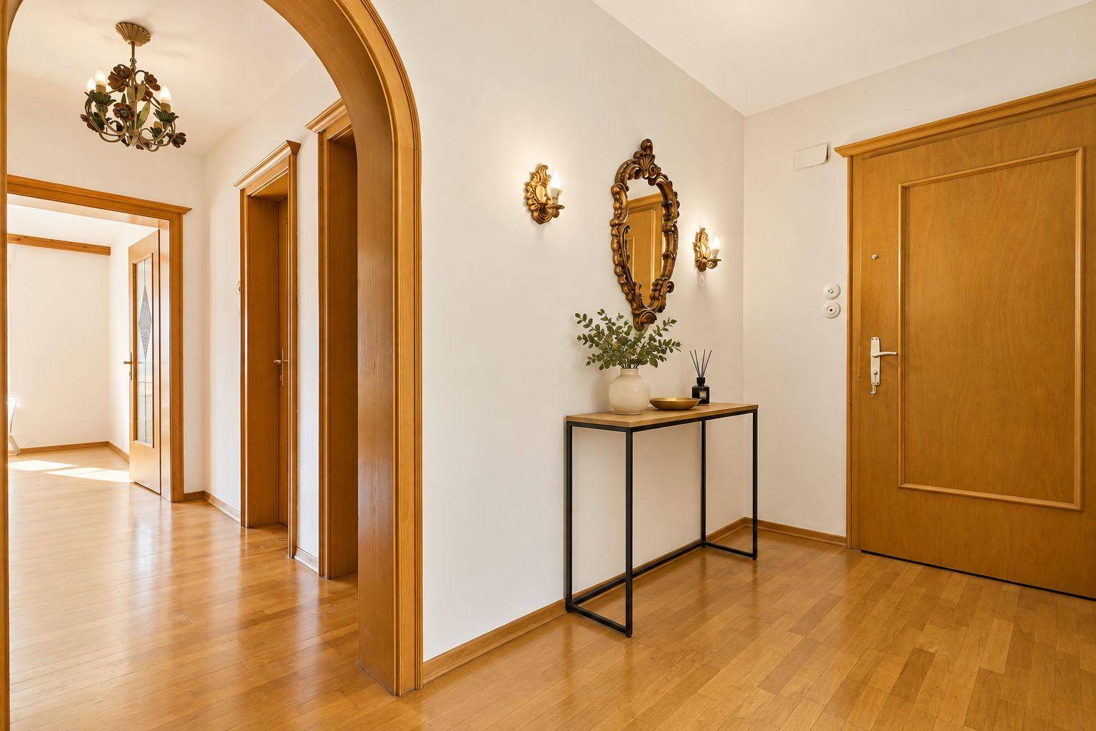 Heller Flur mit Holzparkett, dekorativem Spiegel und traditionellen Holztüren.