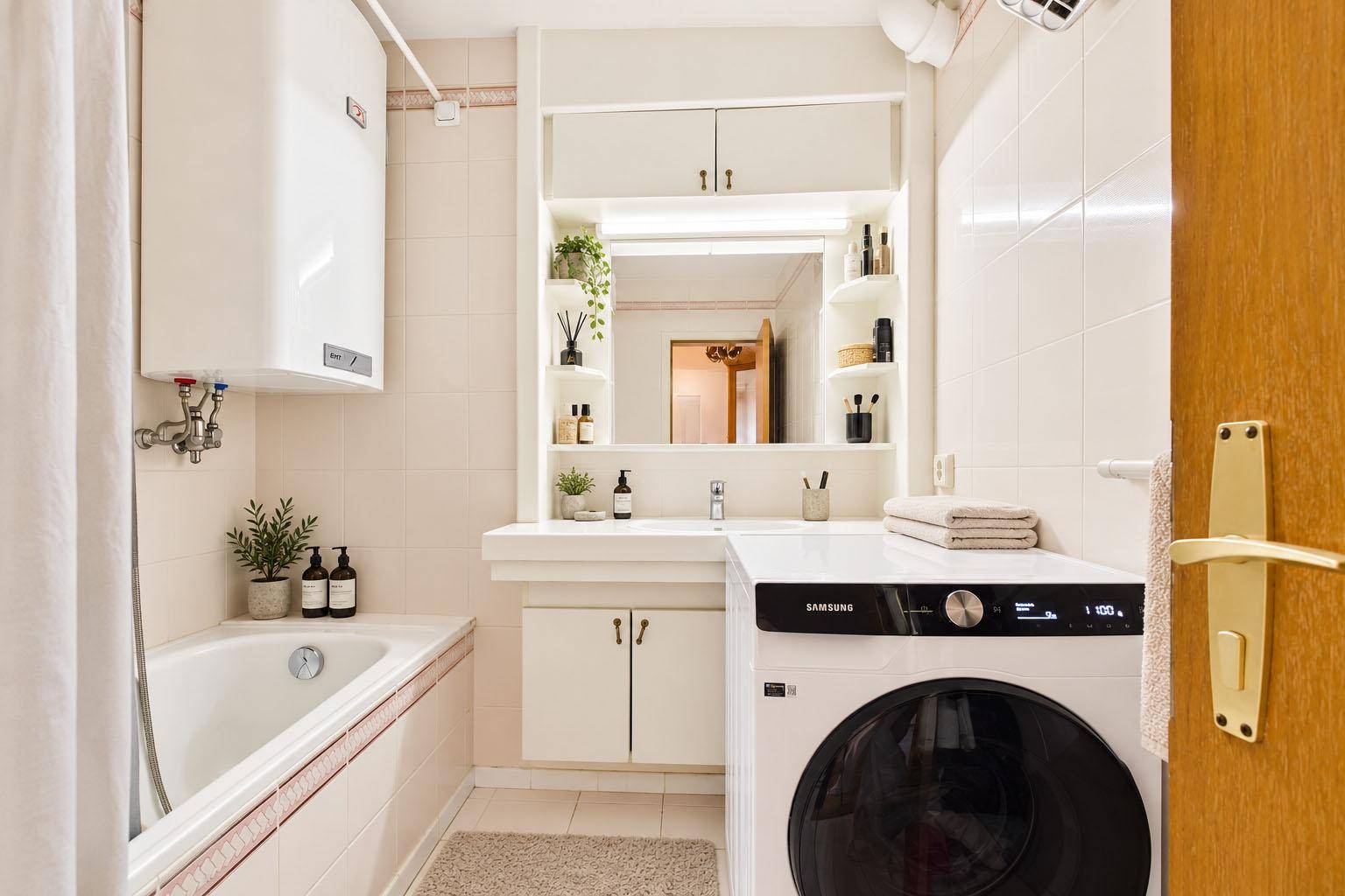 Funktionales Badezimmer mit Badewanne, Waschmaschine und integriertem Spiegelschrank.