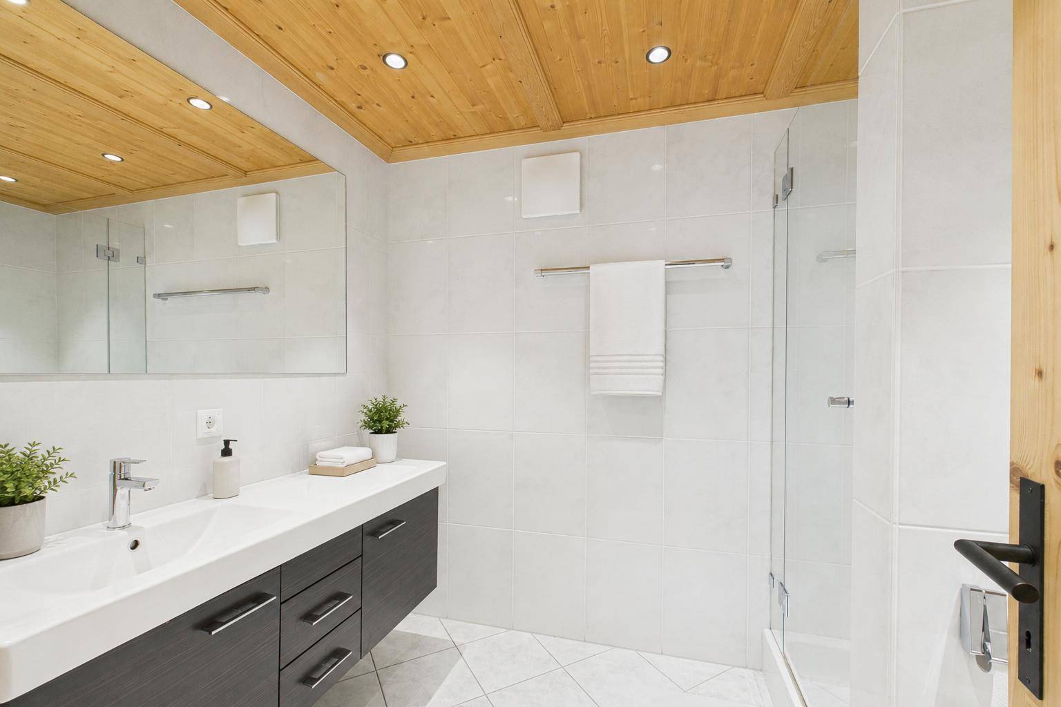Modernes Badezimmer mit Dusche, Waschtisch und Holzbalkendecke.