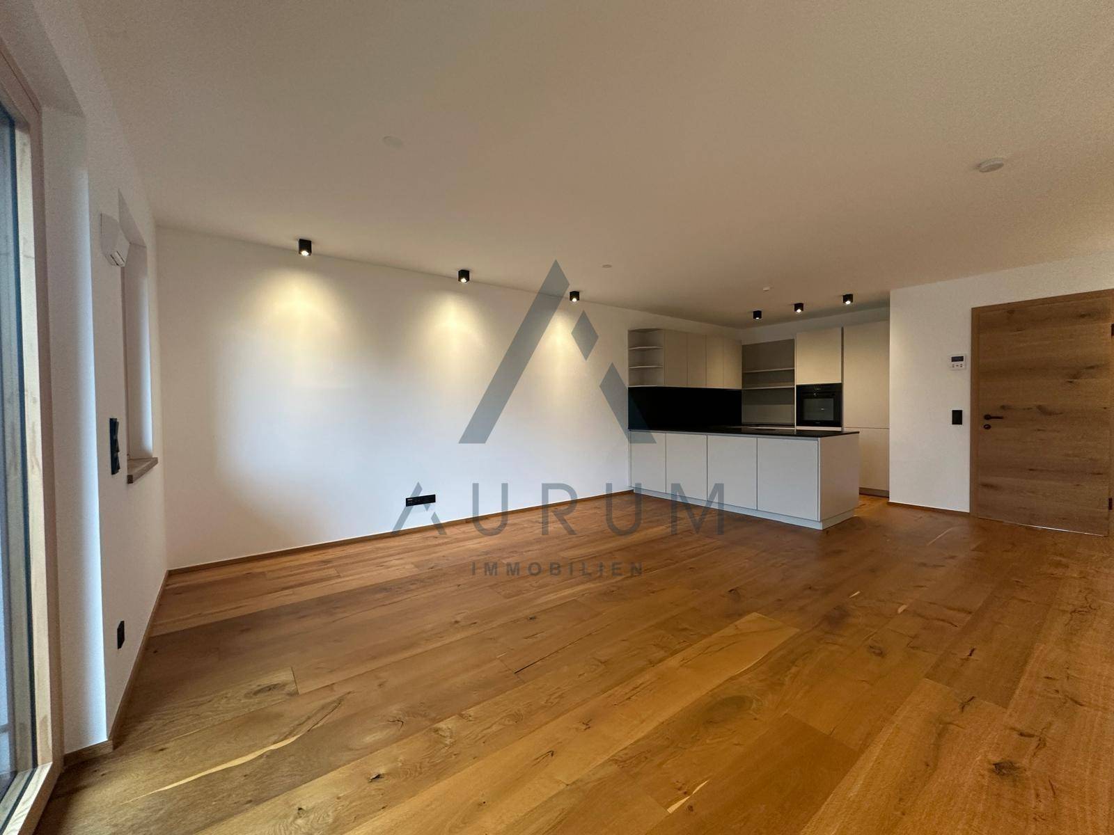 Offener Wohnbereich mit moderner Einbauküche, Holzboden und viel natürlichem Licht.