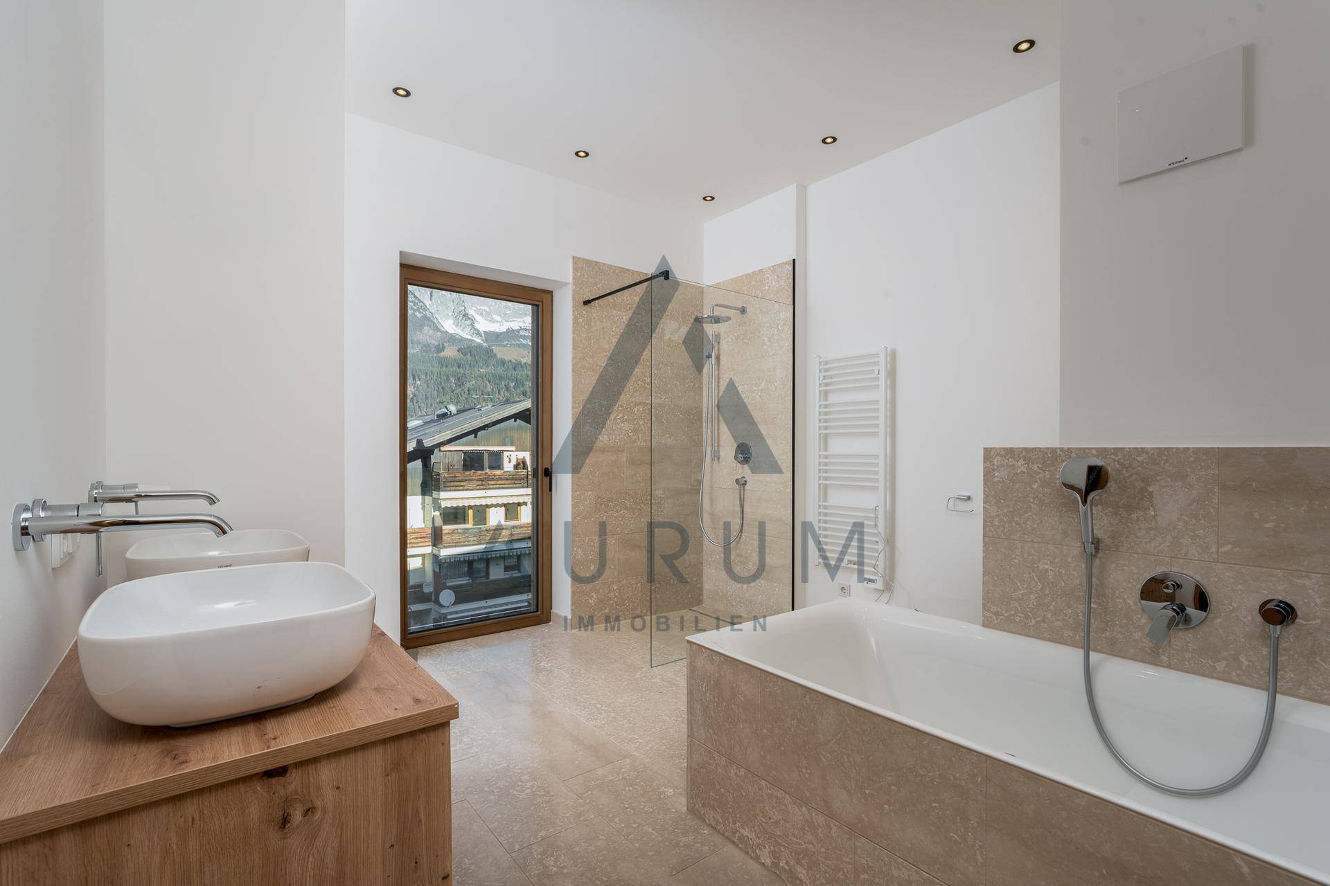 Modernes Badezimmer mit Badewanne, Doppelwaschbecken, Dusche und Fenster mit Bergblick.
