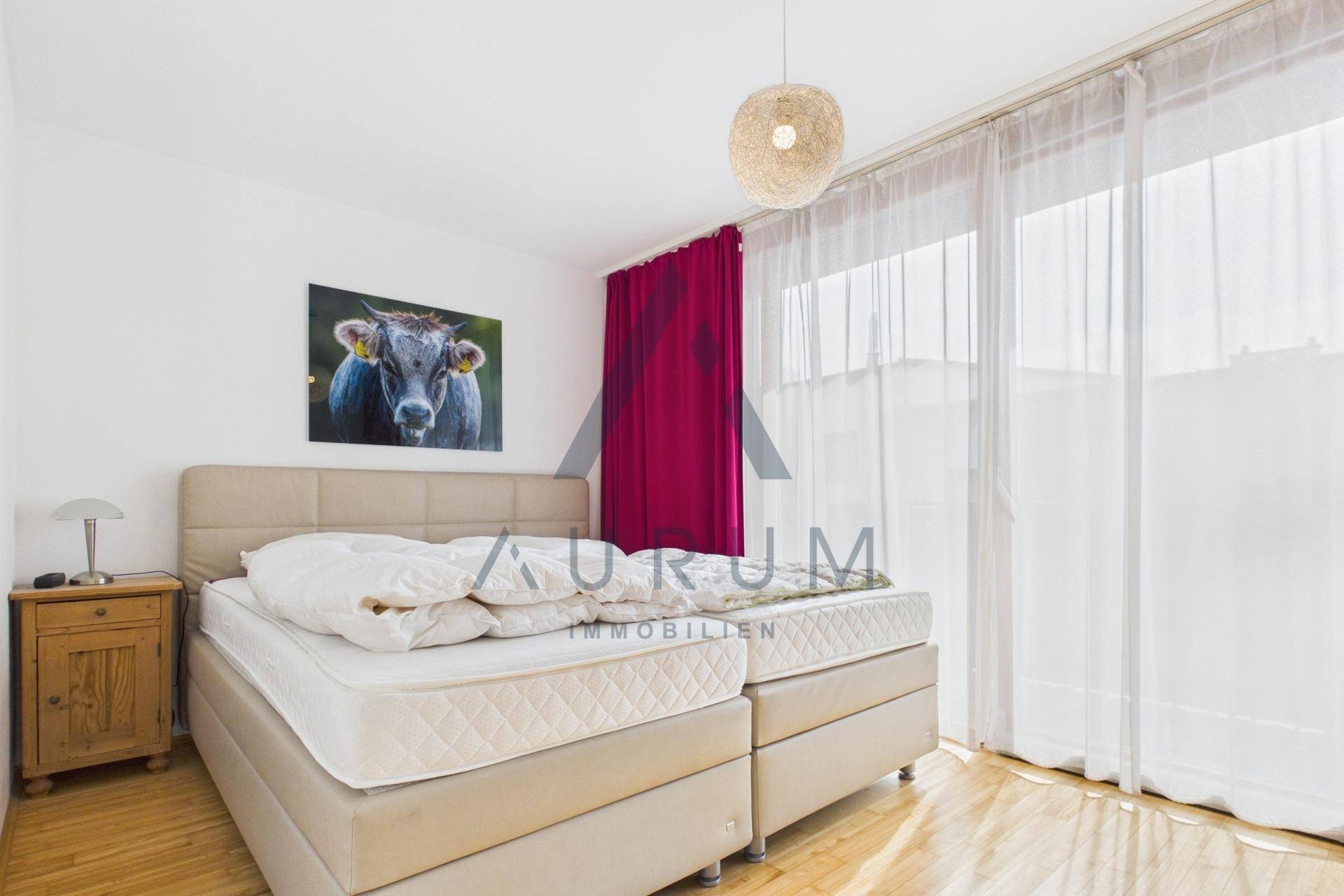 Schlafzimmer mit Doppelbett, Nachttisch und großen Fenstern für viel Tageslicht.