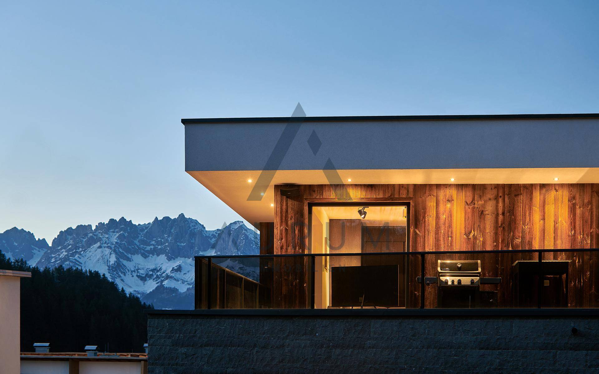 Balkon mit Bergblick und Grillbereich bei Sonnenuntergang, Teil einer modernen Villa.