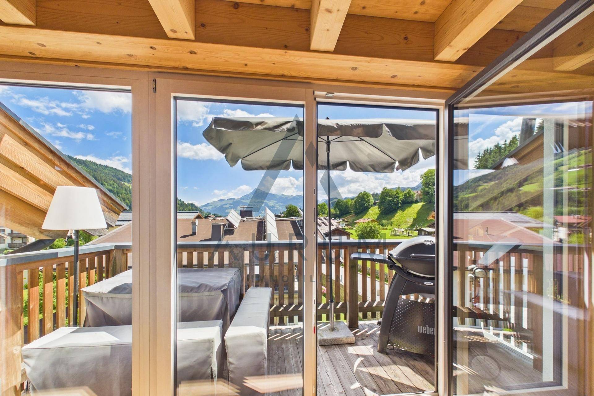 Sonniger Balkon mit Grillbereich, Sitzgelegenheiten und weitem Blick auf die Berge.