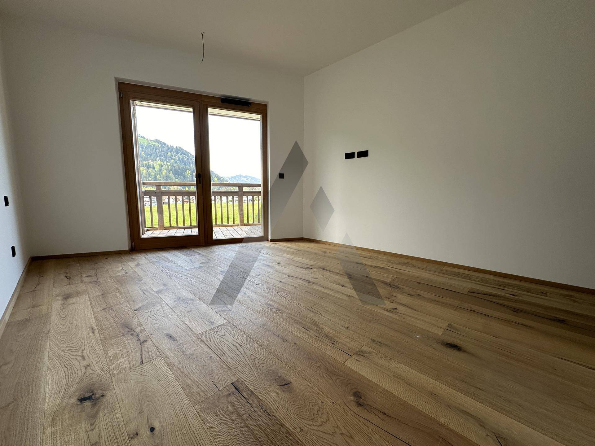 Helles Schlafzimmer mit Holzboden und Balkonzugang, bietet einen schönen Blick auf die Umgebung.