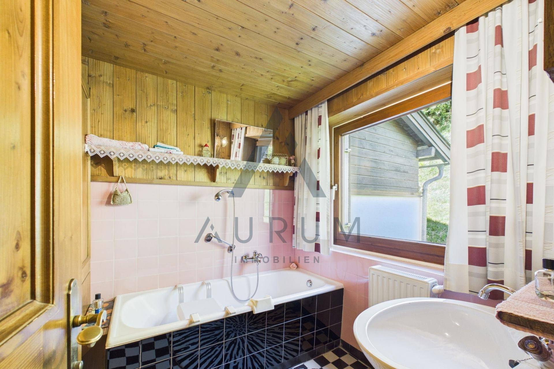 Traditionelles Badezimmer mit Badewanne, Holzvertäfelung und rosa Fliesen.