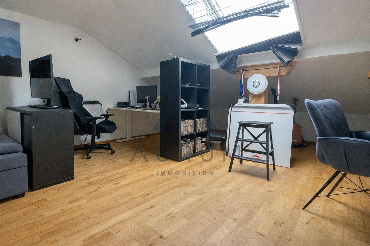 Geräumiges Arbeitszimmer im Dachgeschoss mit Holzboden, Schreibtischen und Dachfenster.