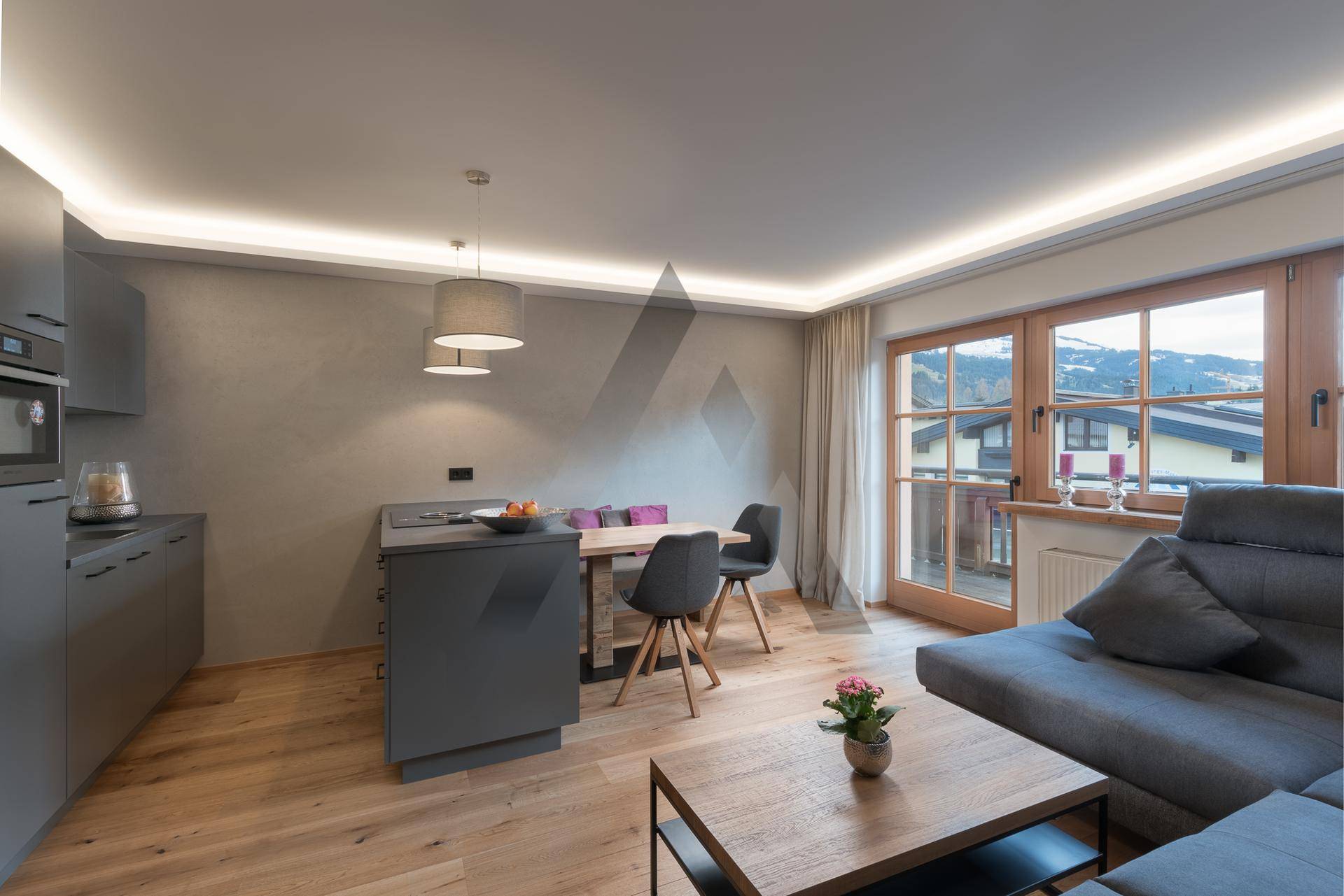 Lichtdurchfluteter Wohn-Essbereich mit moderner Einrichtung und Panoramablick auf die Berge.