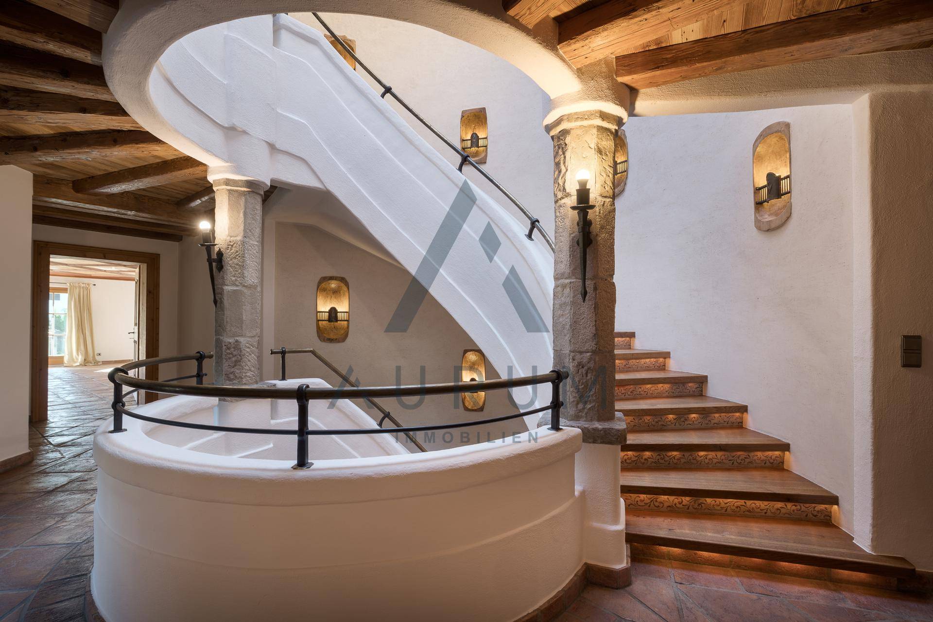 Beeindruckendes Treppenhaus mit geschwungener Steintreppe und indirekter Beleuchtung.
