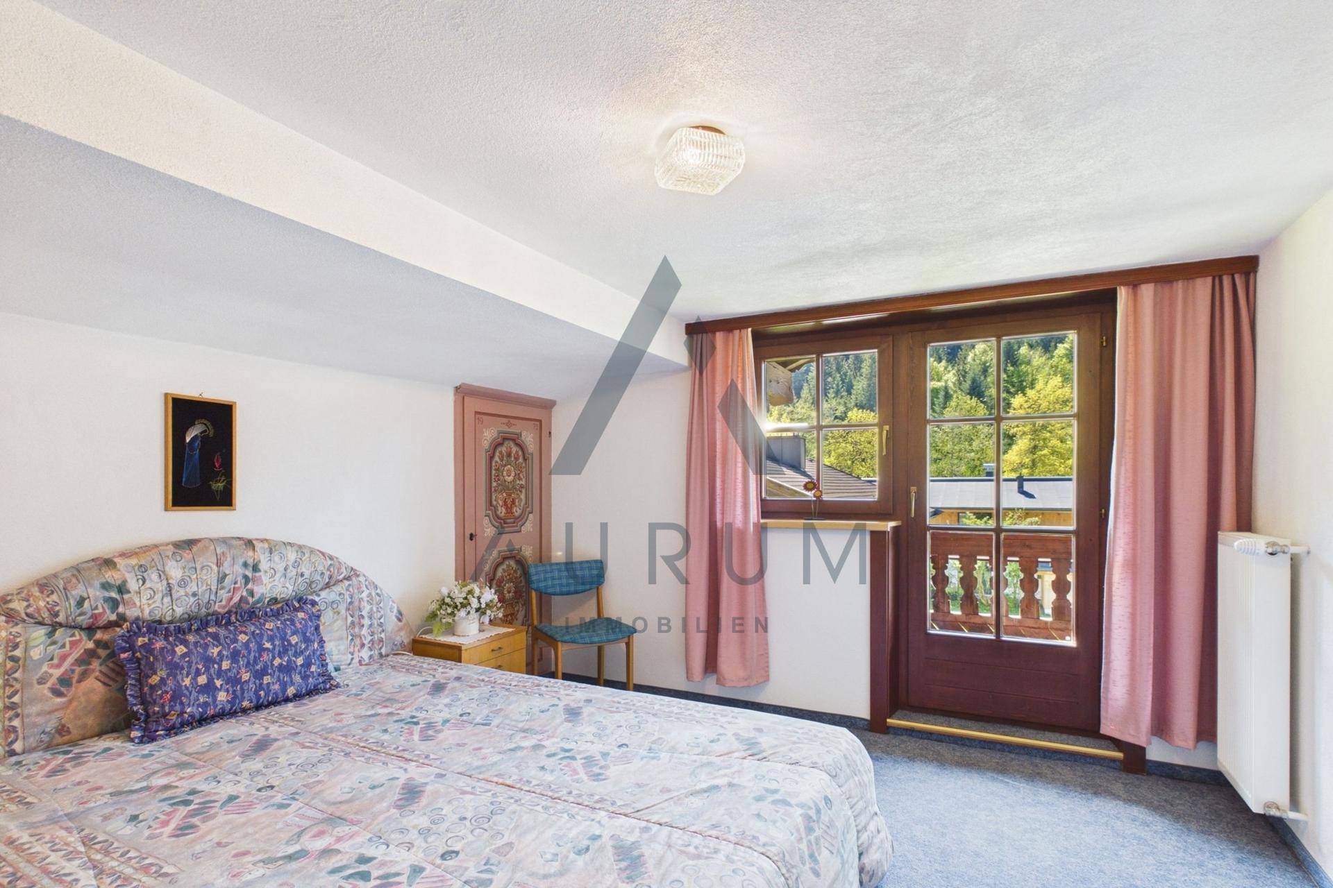 Gemütliches Schlafzimmer mit Teppichboden, Dachschräge und Zugang zum Balkon.