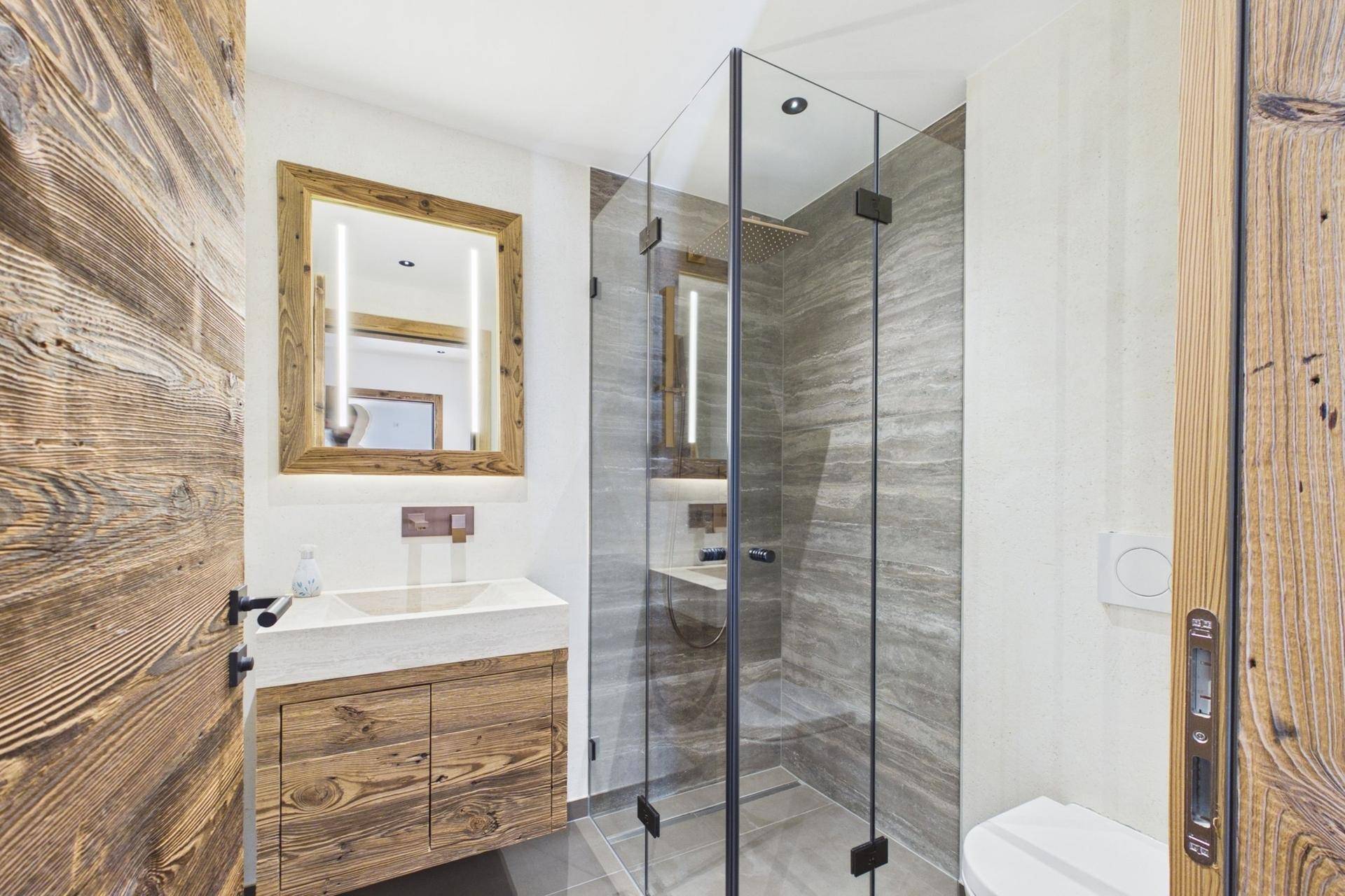 Modernes Badezimmer mit begehbarer Dusche, Holzwaschtisch und großem Spiegel.